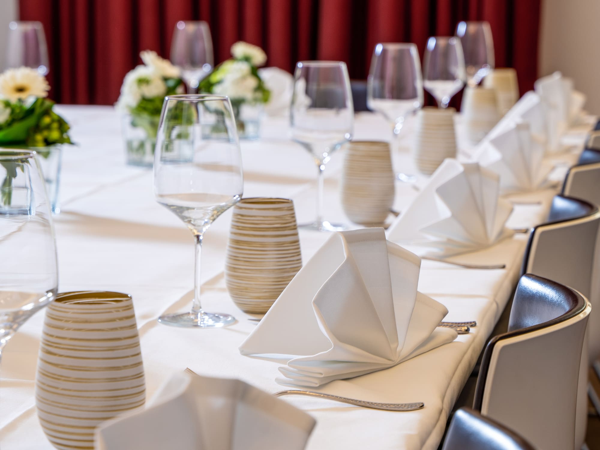 Elegant event dining table with wine glasses, white napkins, and floral decor.
