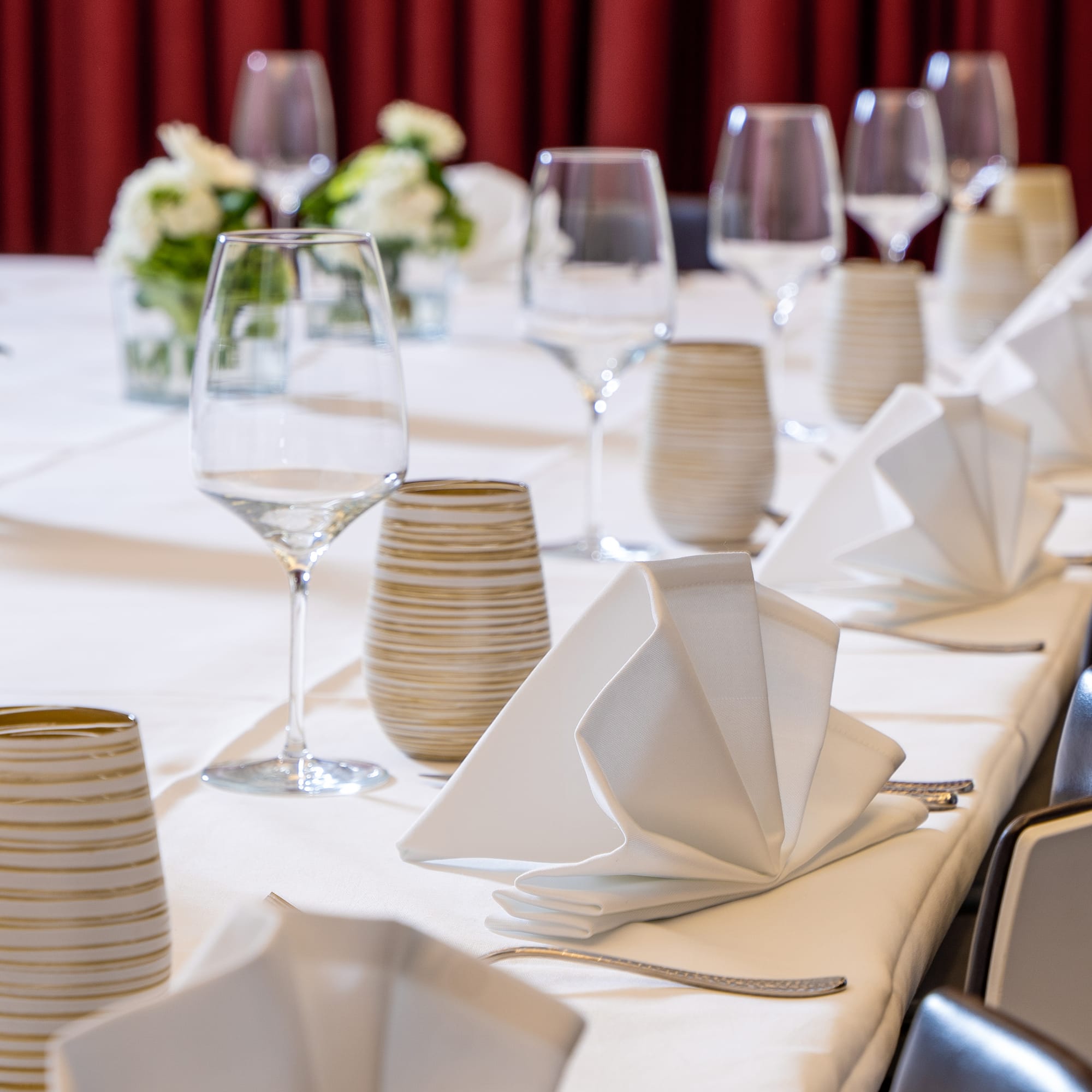 Elegant event dining table with wine glasses, white napkins, and floral decor.