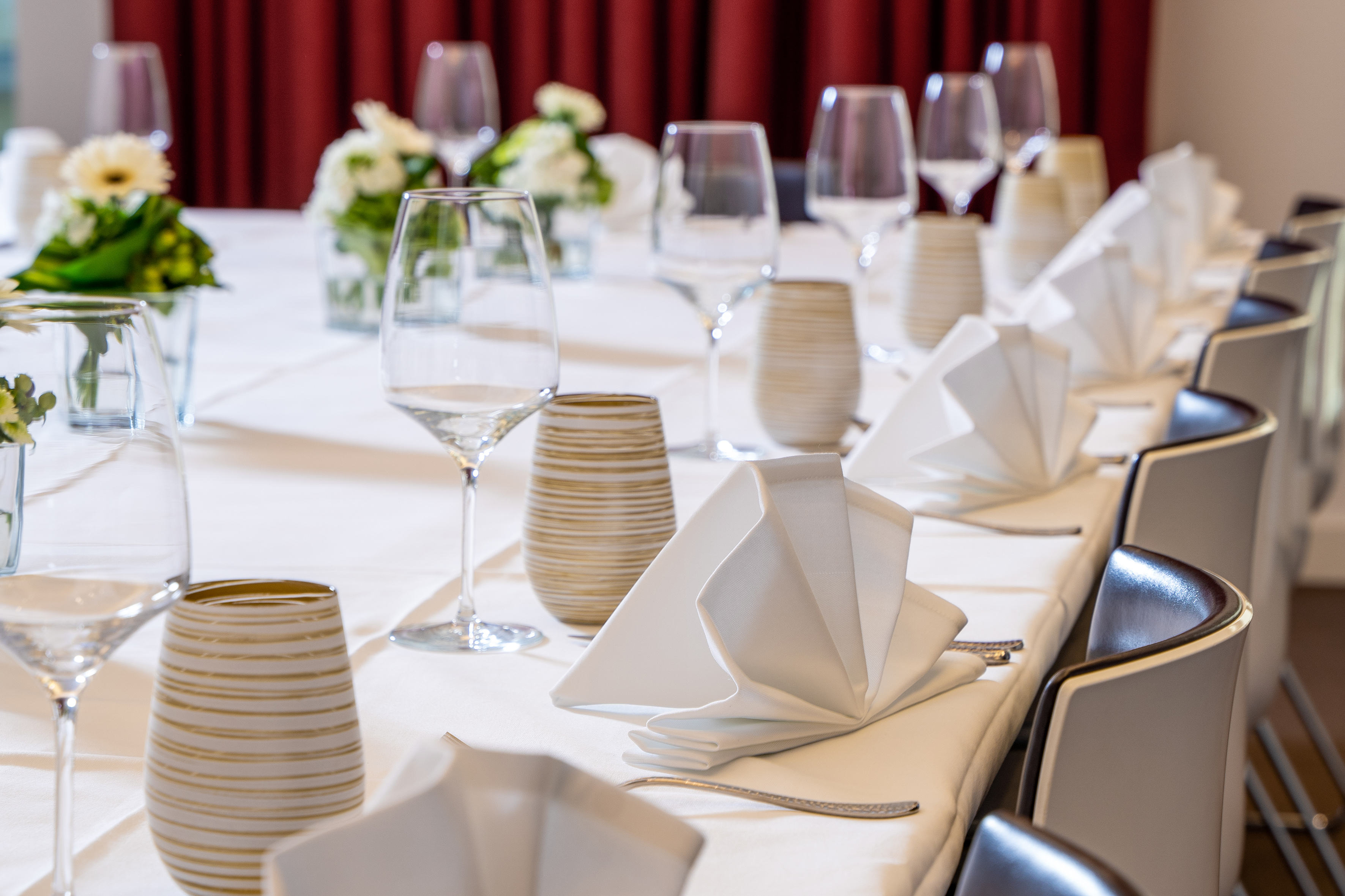 Elegant event dining table with wine glasses, white napkins, and floral decor.