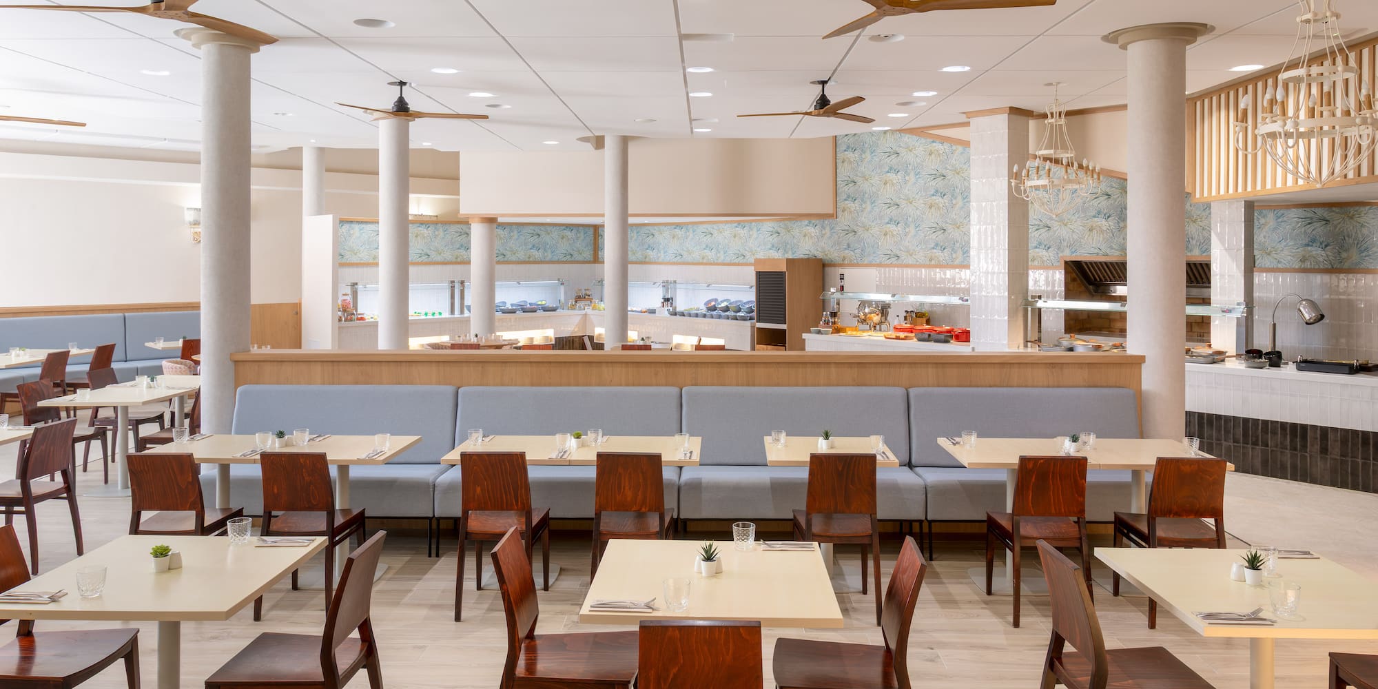 Spacious modern buffet restaurant interior with light wood tables and ceiling fans.