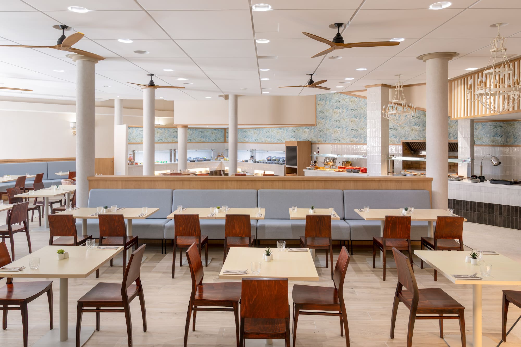 Spacious modern buffet restaurant interior with light wood tables and ceiling fans.