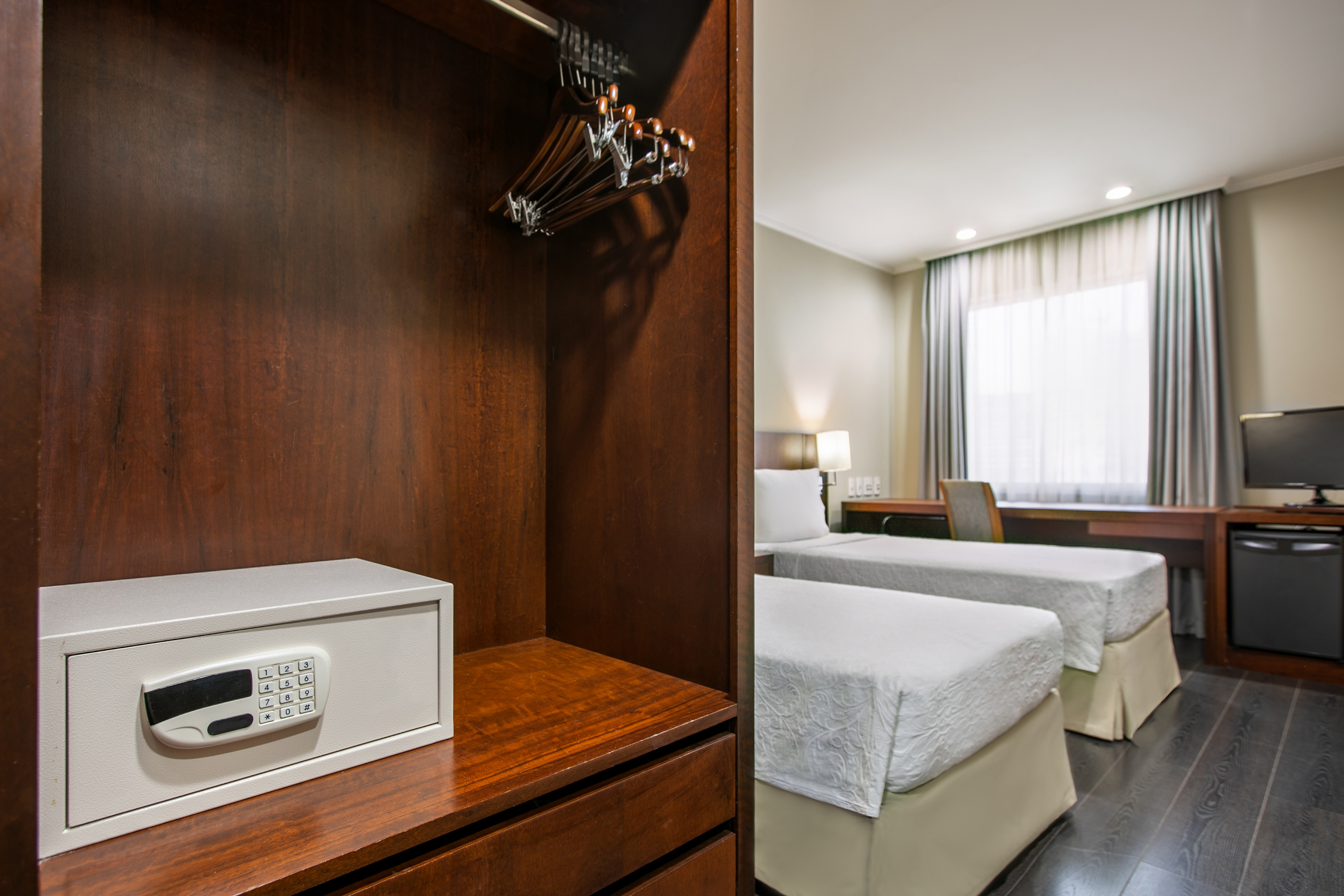 Digital safe in dark hotel wardrobe. Twin beds and desk in background.