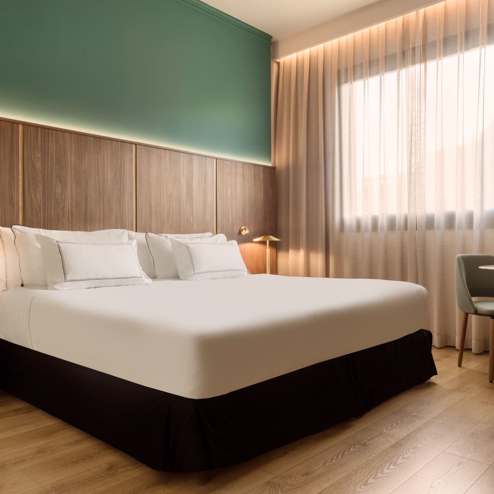 a bed with white sheets and a chair in a room