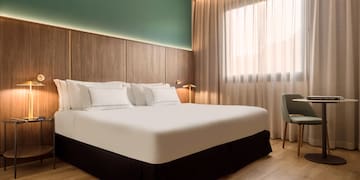 a bed with white sheets and a chair in a room