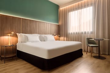 a bed with white sheets and a chair in a room