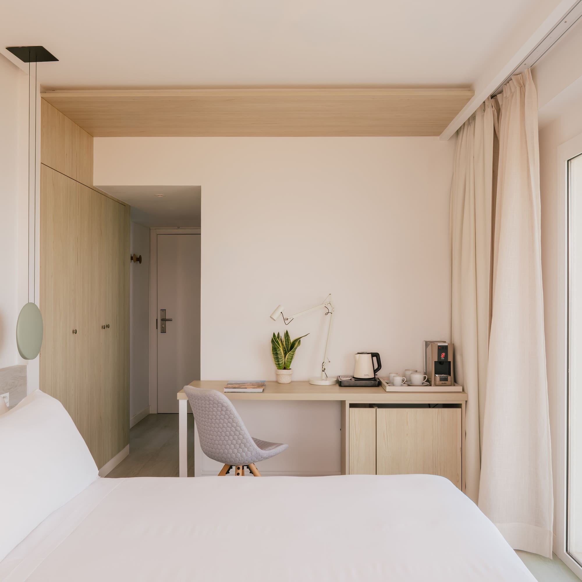 Modern hotel bedroom with sea view, desk, and coffee station.