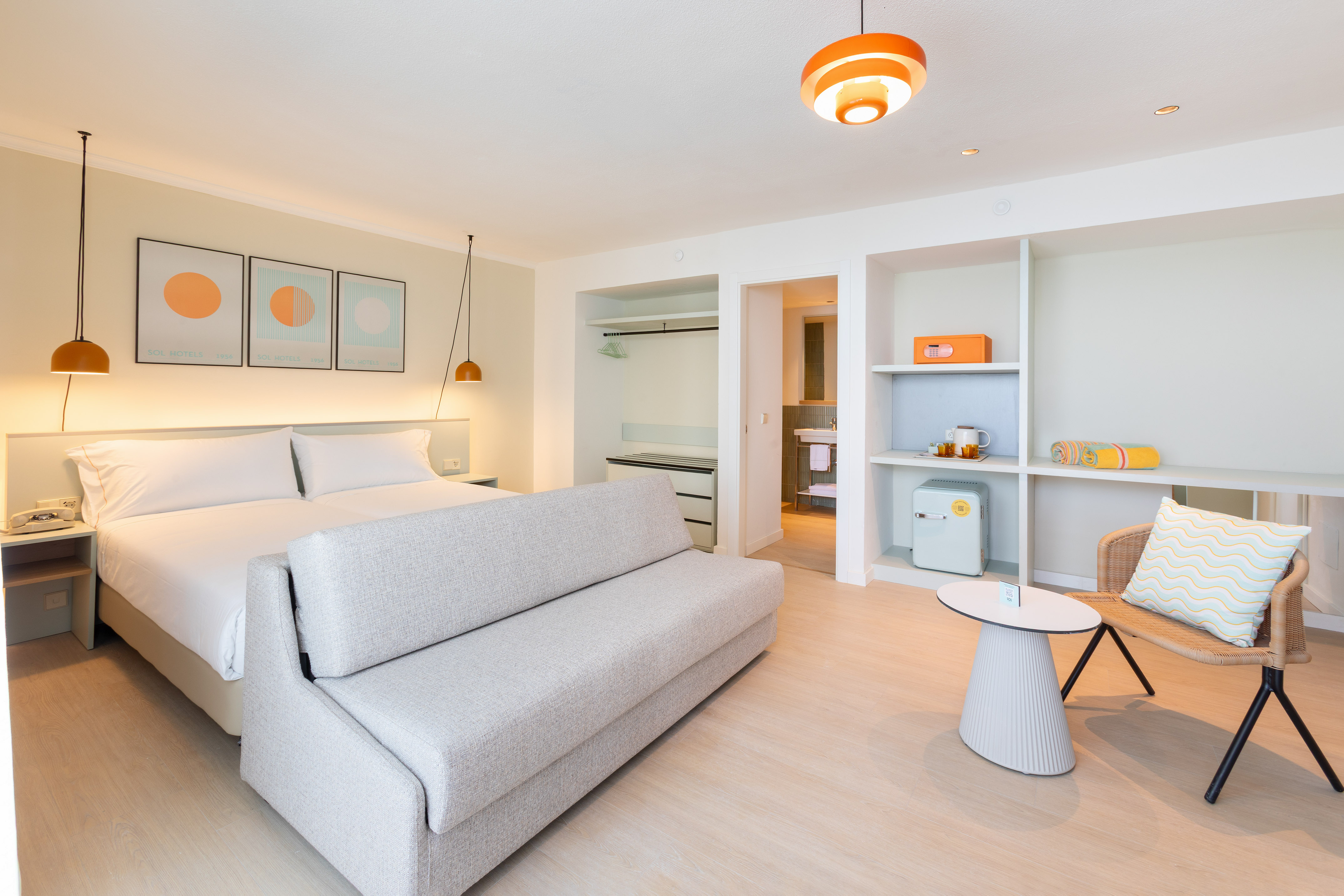Sol Hotels room with bed, sofa bed, mini-fridge, and bright modern decor.