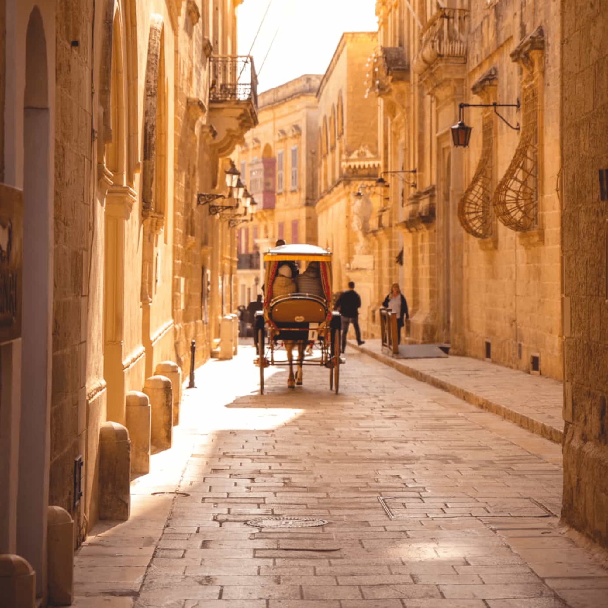 Sunny Mdina street, karrozzin, ancient stone buildings, Malta.