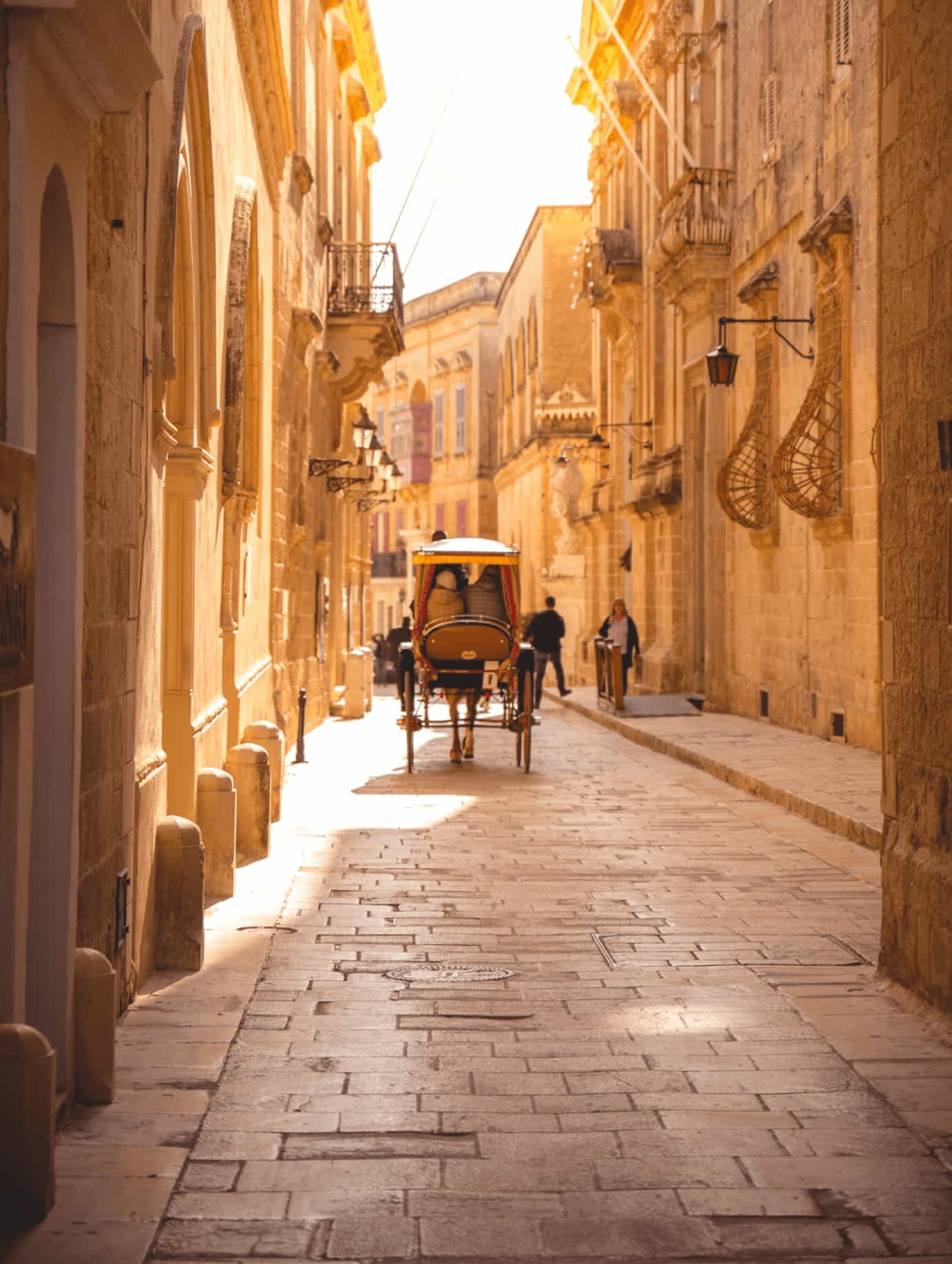 Sunny Mdina street, karrozzin, ancient stone buildings, Malta.