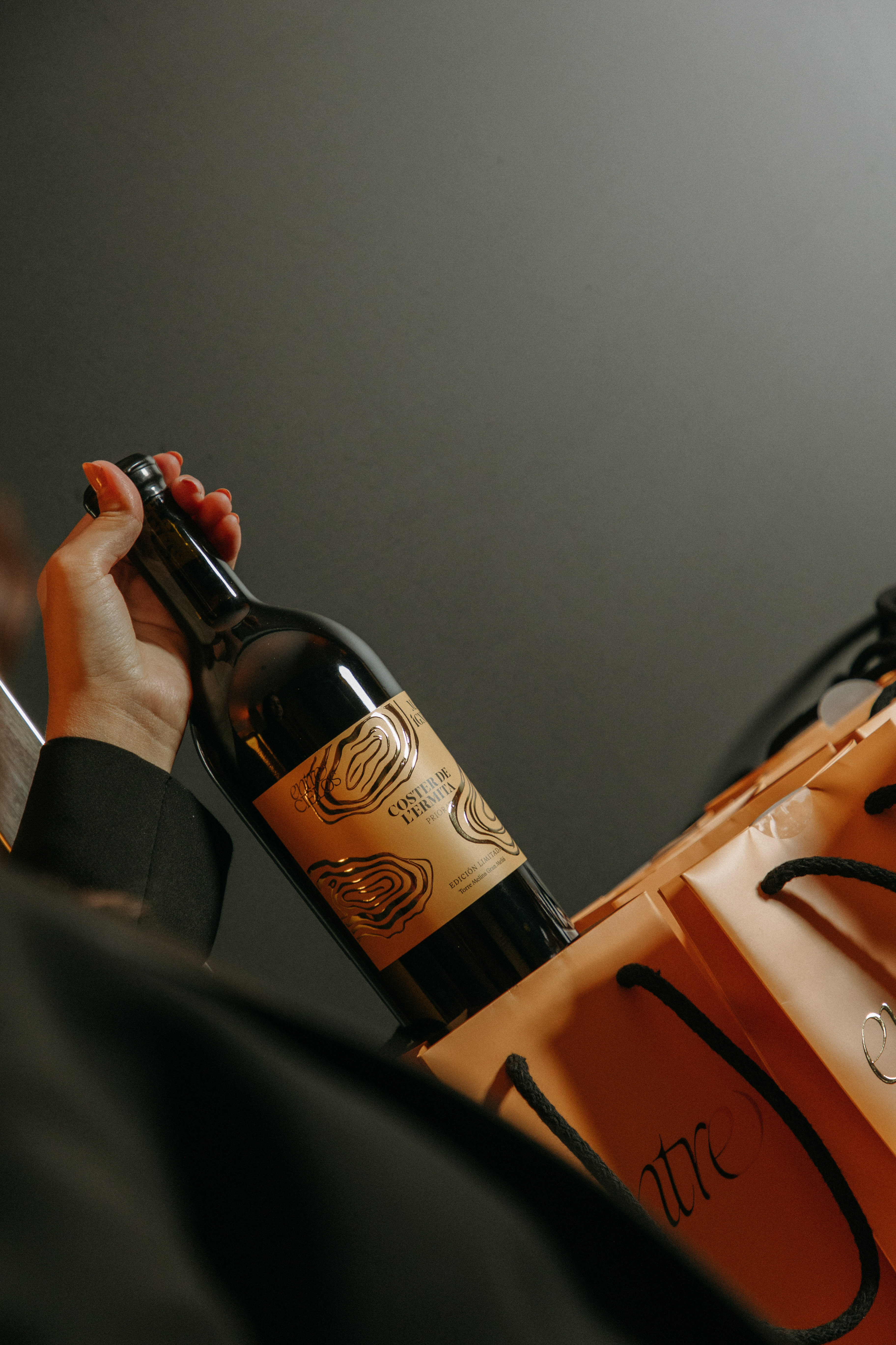 Hand holding Coster de l'Ermita Priorat red wine bottle in orange gift bag.