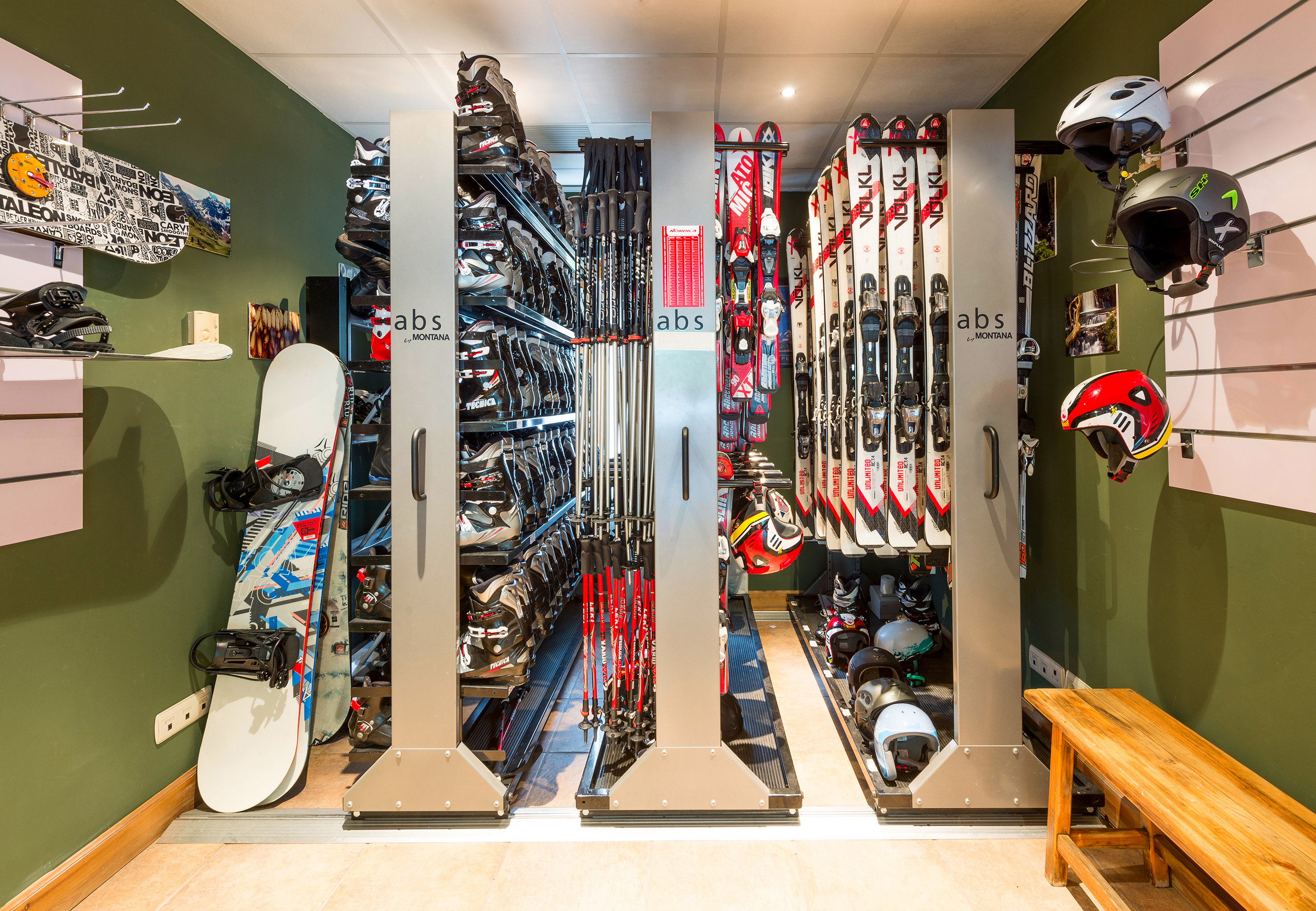Ski and snowboard rental gear storage with boots, skis, helmets, and poles.
