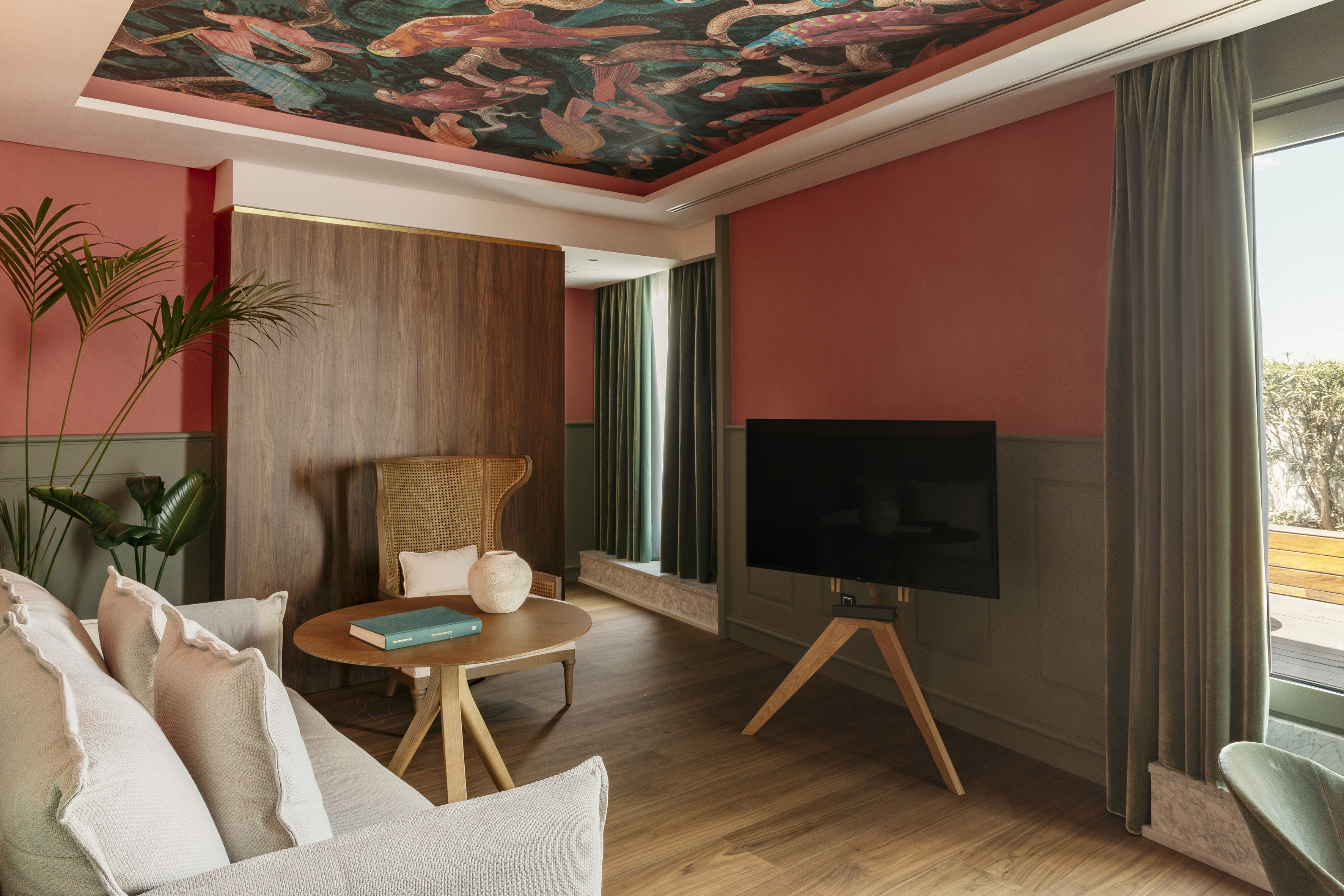 Vibrant living room with aquatic ceiling design, coral walls, and wood floor.