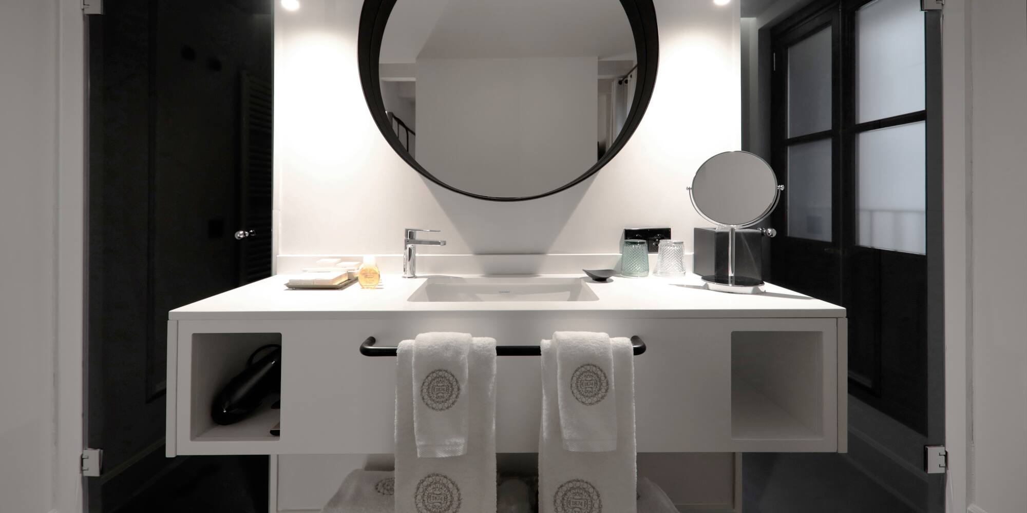 a bathroom with a round mirror and white towels