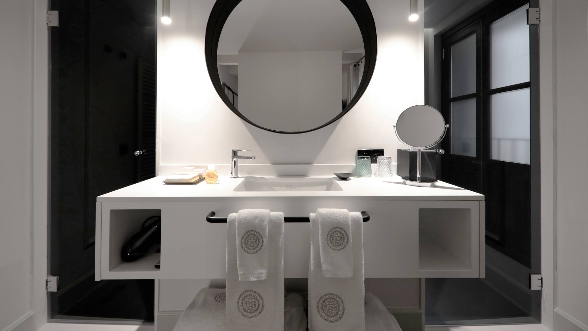 a bathroom with a round mirror and white towels