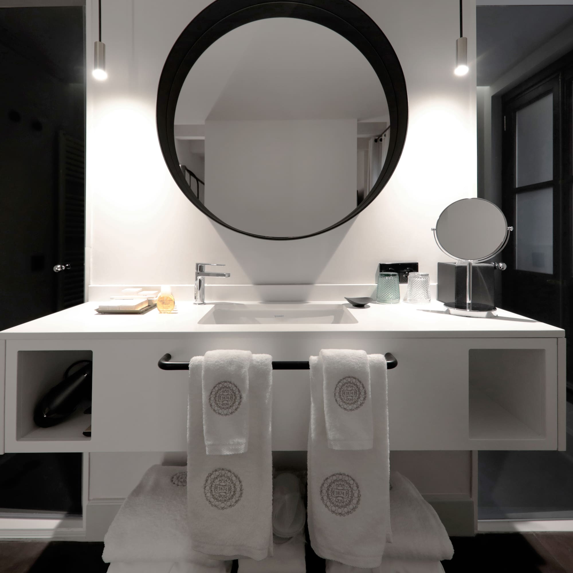 a bathroom with a round mirror and white towels