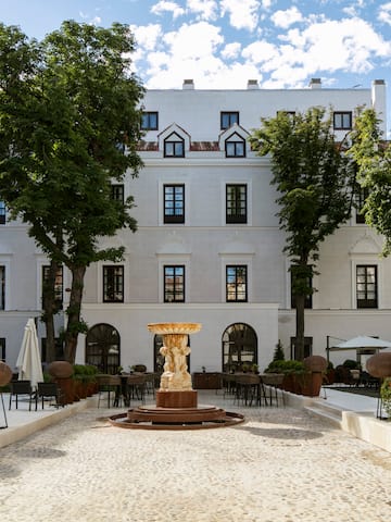 a courtyard with a fountain and trees in front of a building