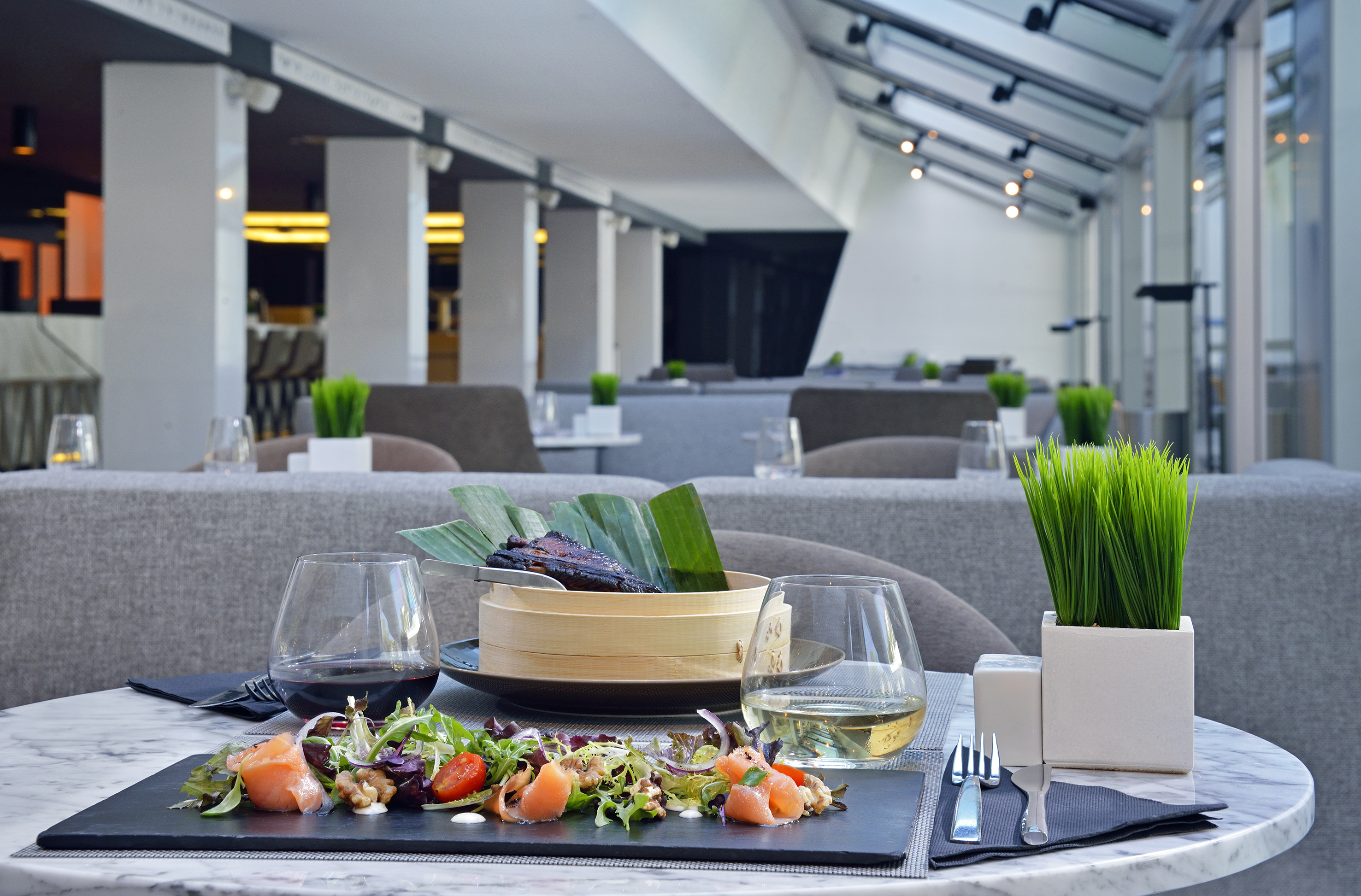 Elegant restaurant table with gourmet salmon salad, steamed dish, and wine.