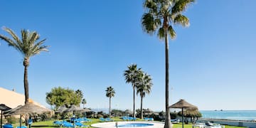 a pool with lounge chairs and umbrellas by a beach