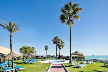 a pool with lounge chairs and umbrellas by a beach