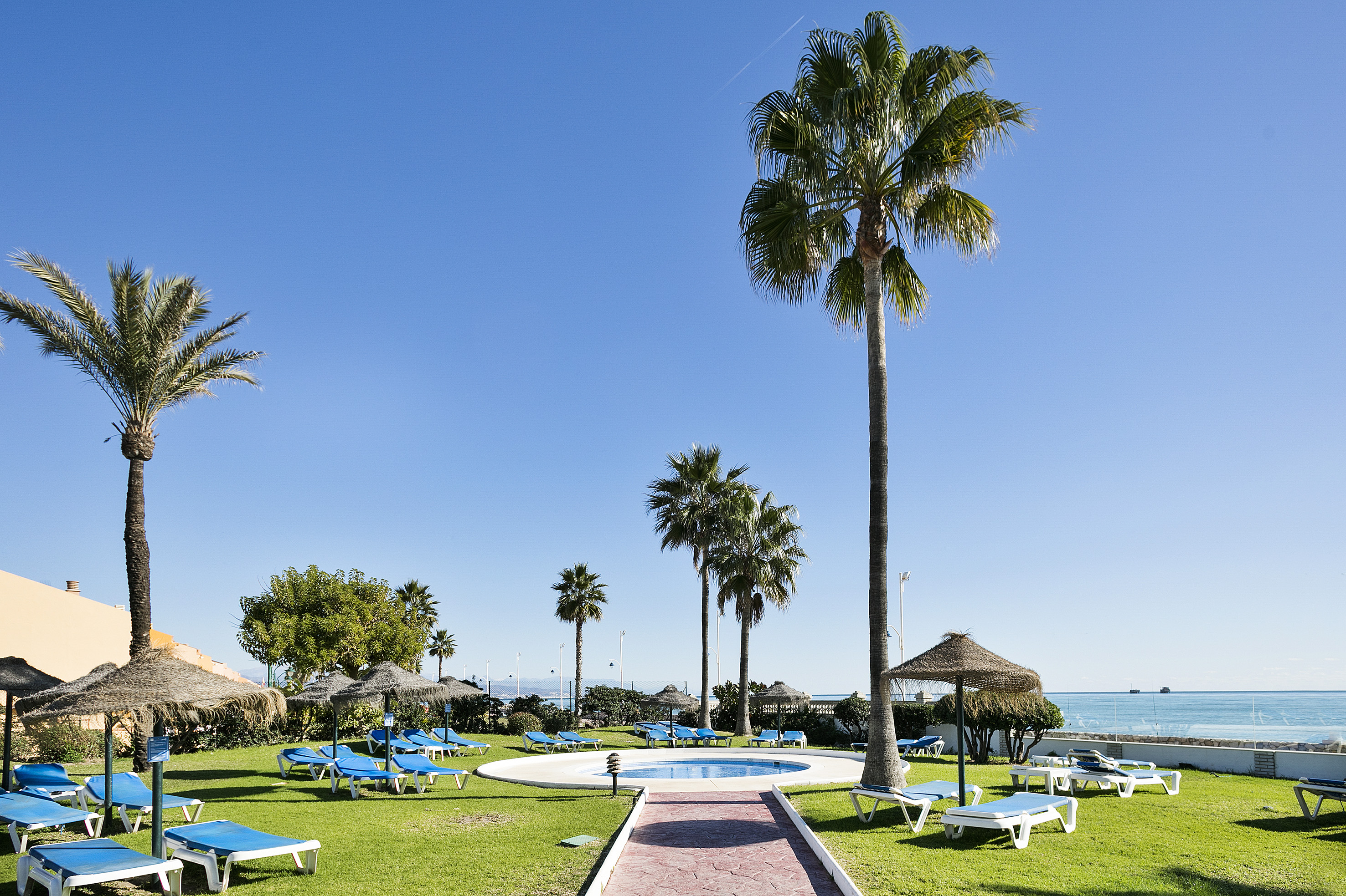 a pool with lounge chairs and umbrellas by a beach