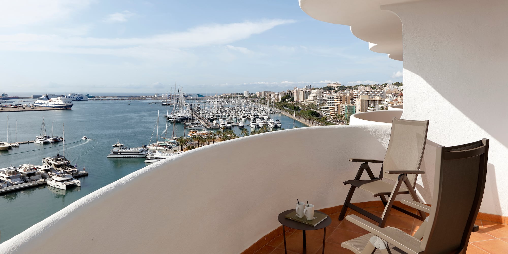 a balcony with chairs and a view of the water and boats