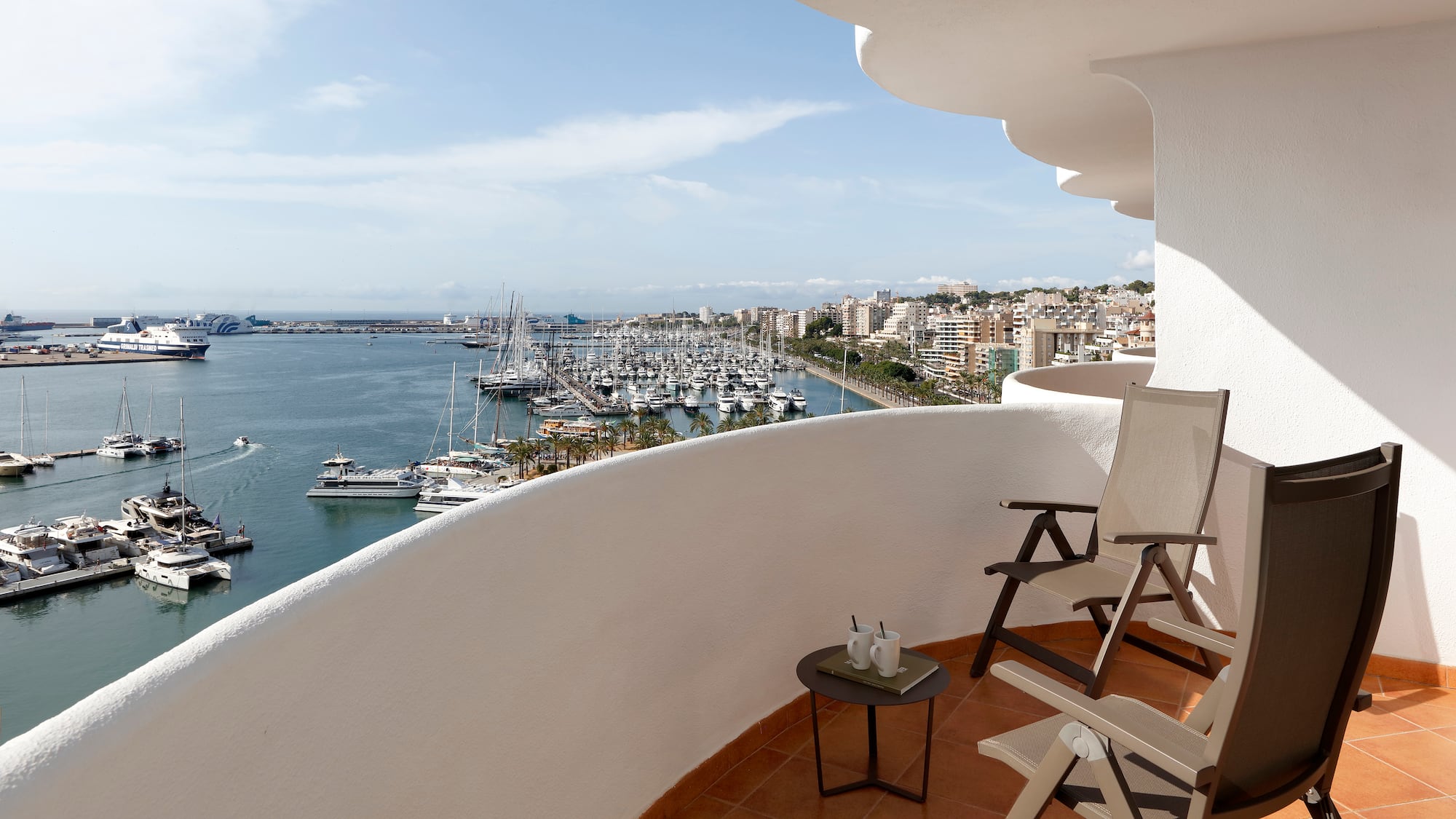 a balcony with chairs and a view of the water and boats