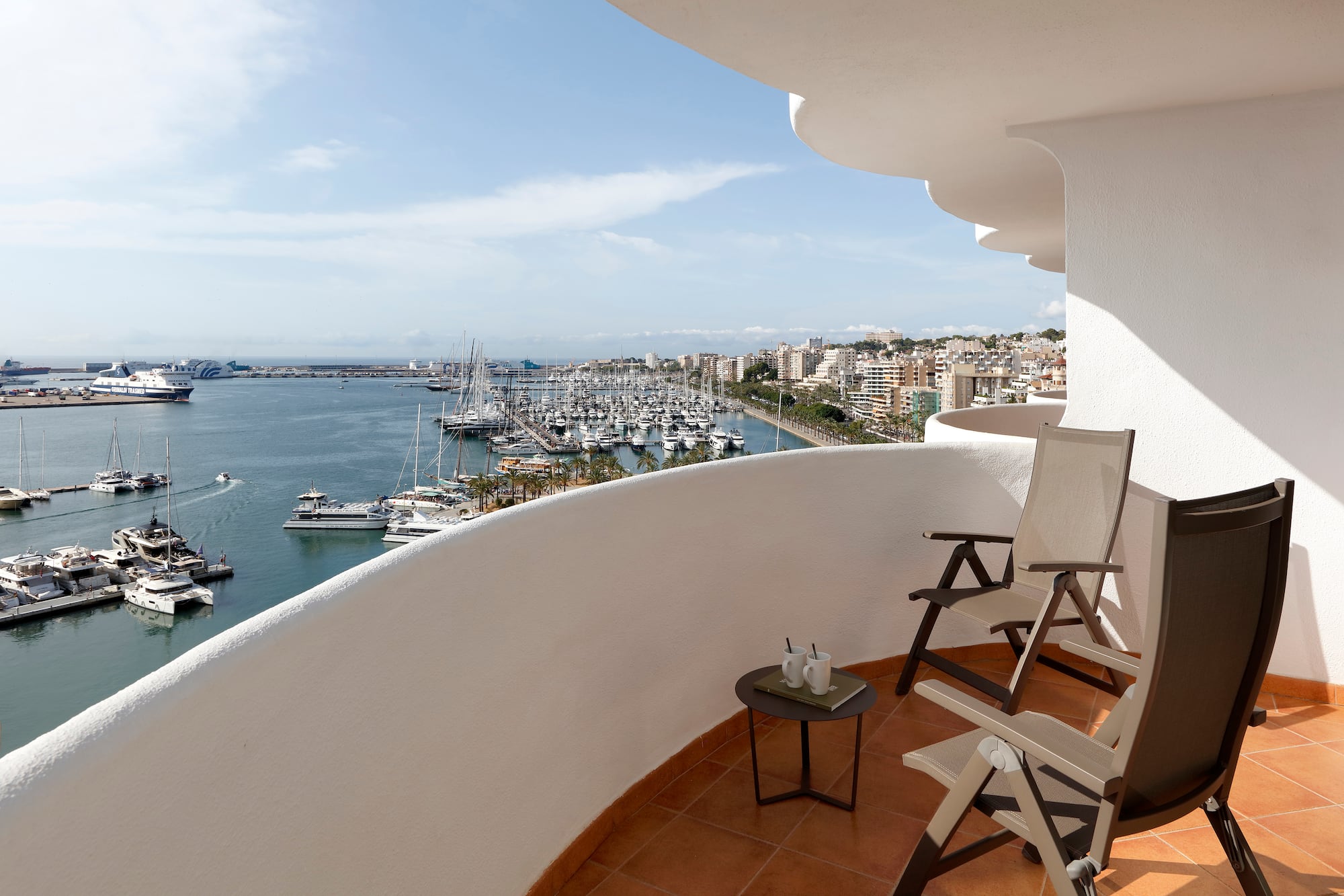 a balcony with chairs and a view of the water and boats