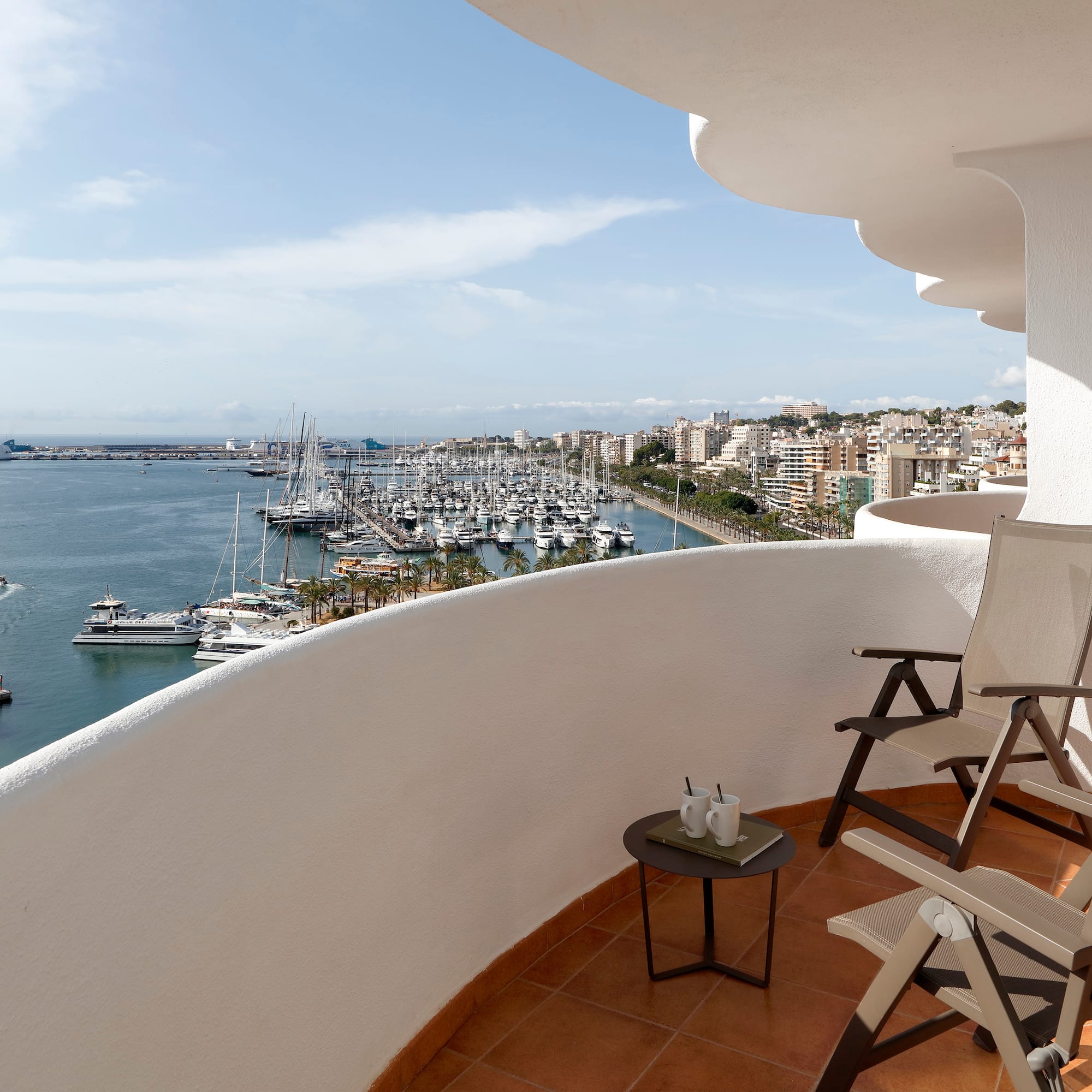a balcony with chairs and a view of the water and boats