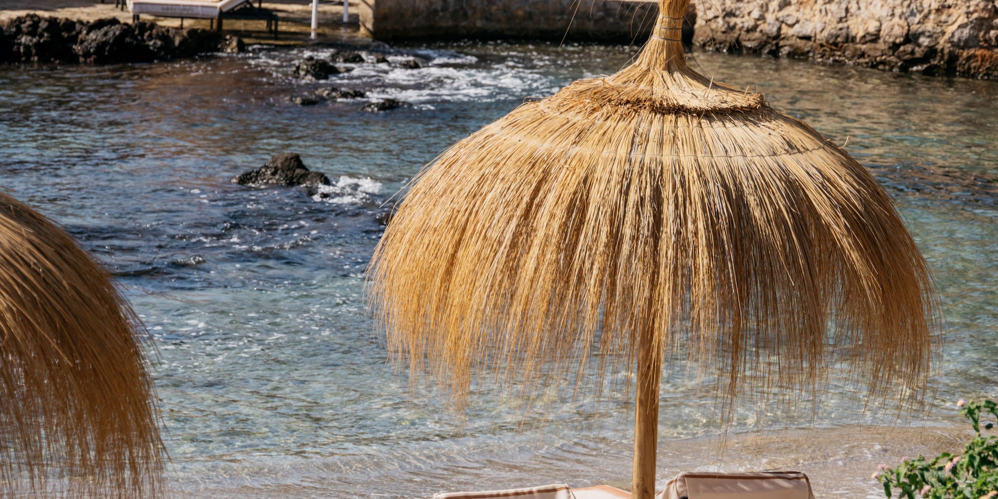 a beach with a straw umbrella and chairs.