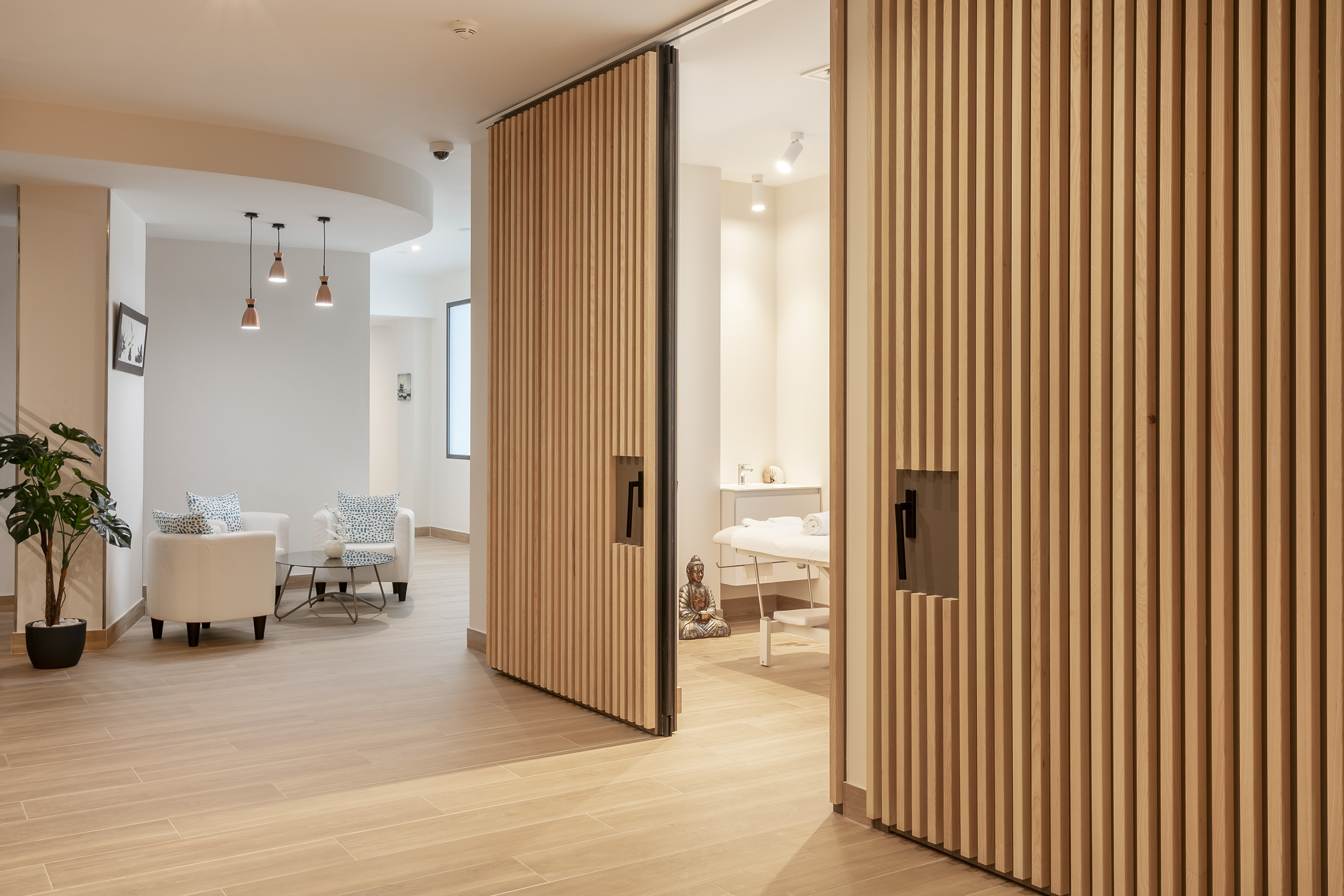 Modern spa waiting area with slatted wood doors leading to a treatment room.