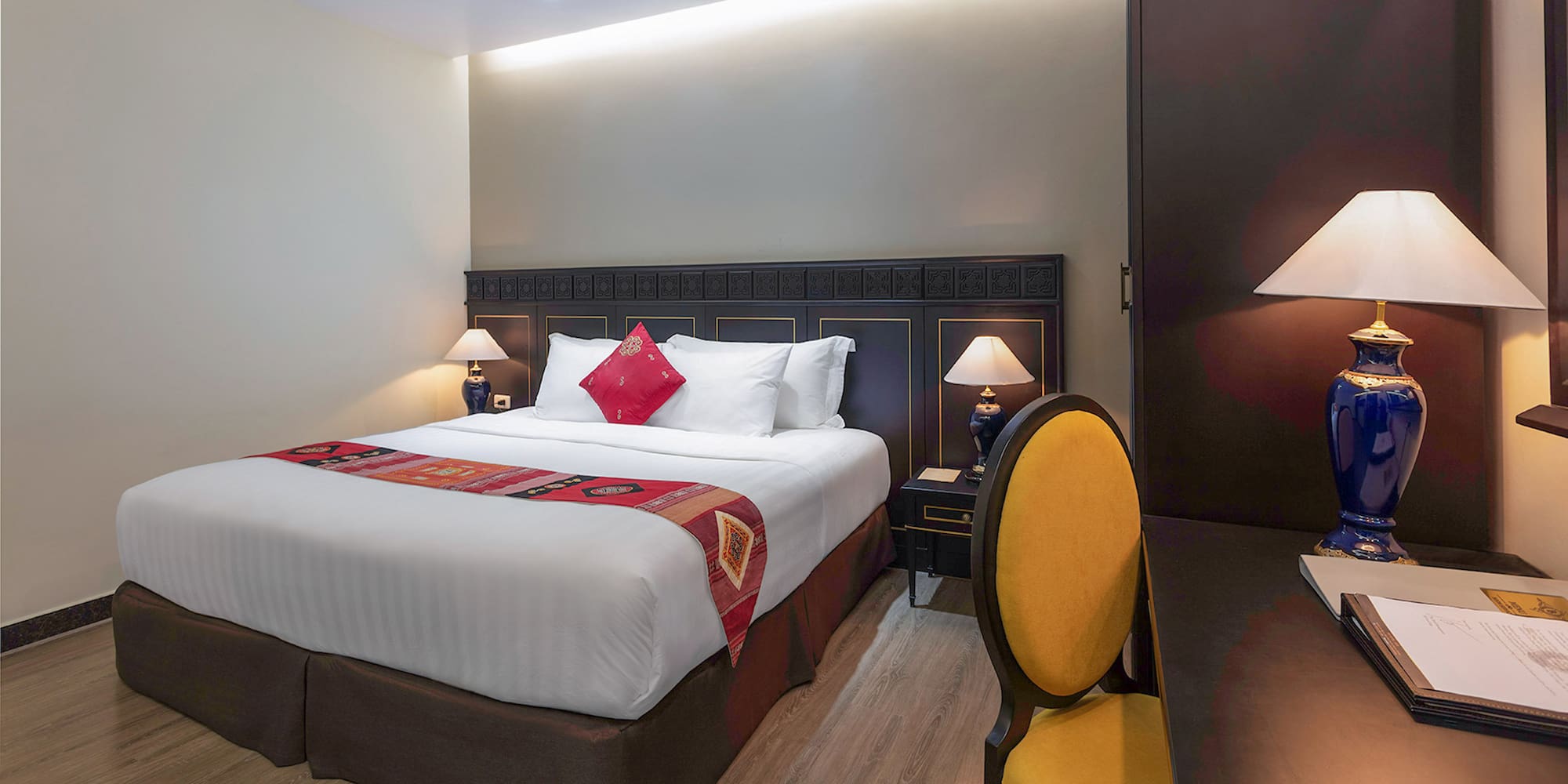 a bed with a red pillow and a yellow chair