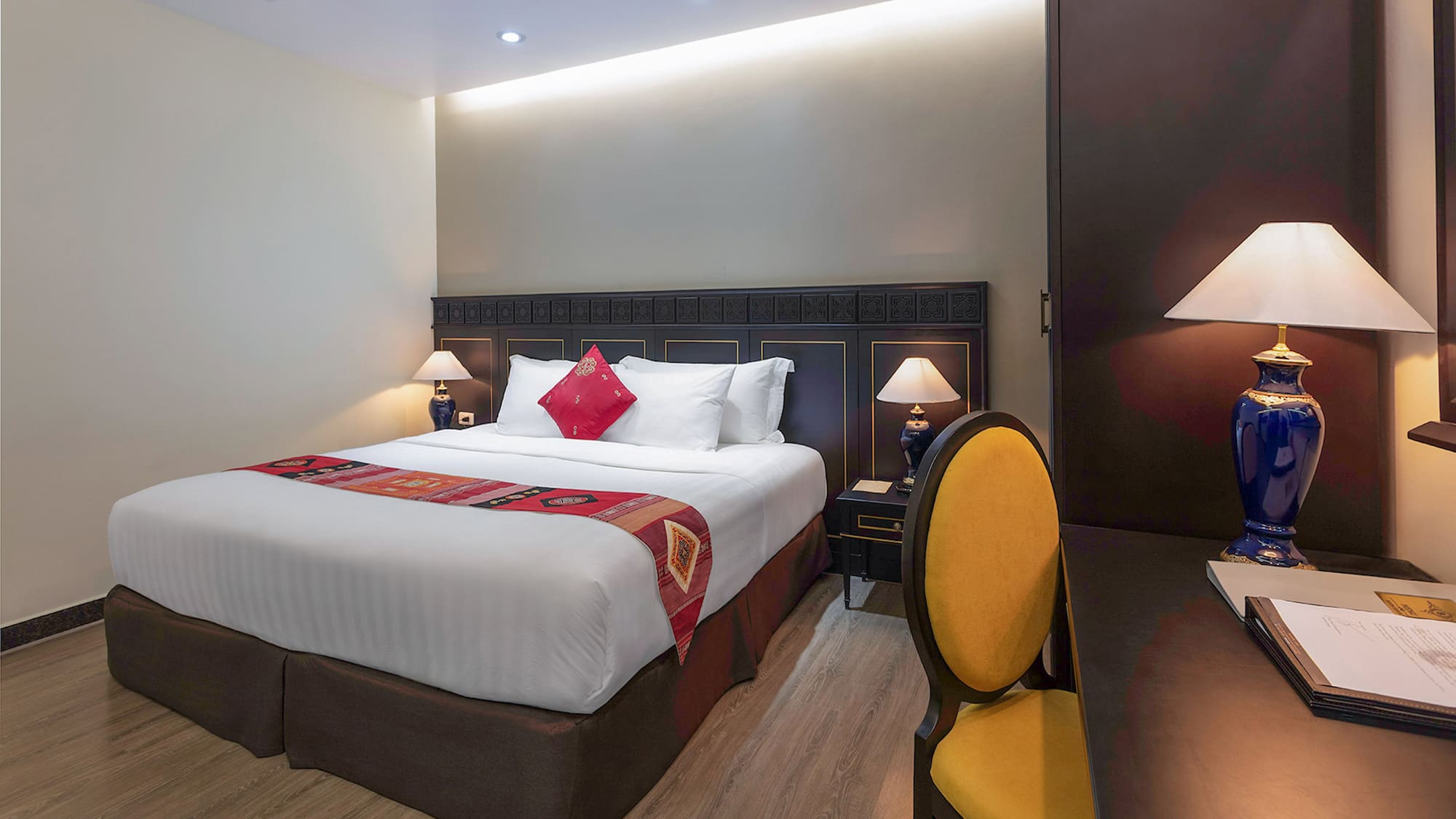 a bed with a red pillow and a yellow chair