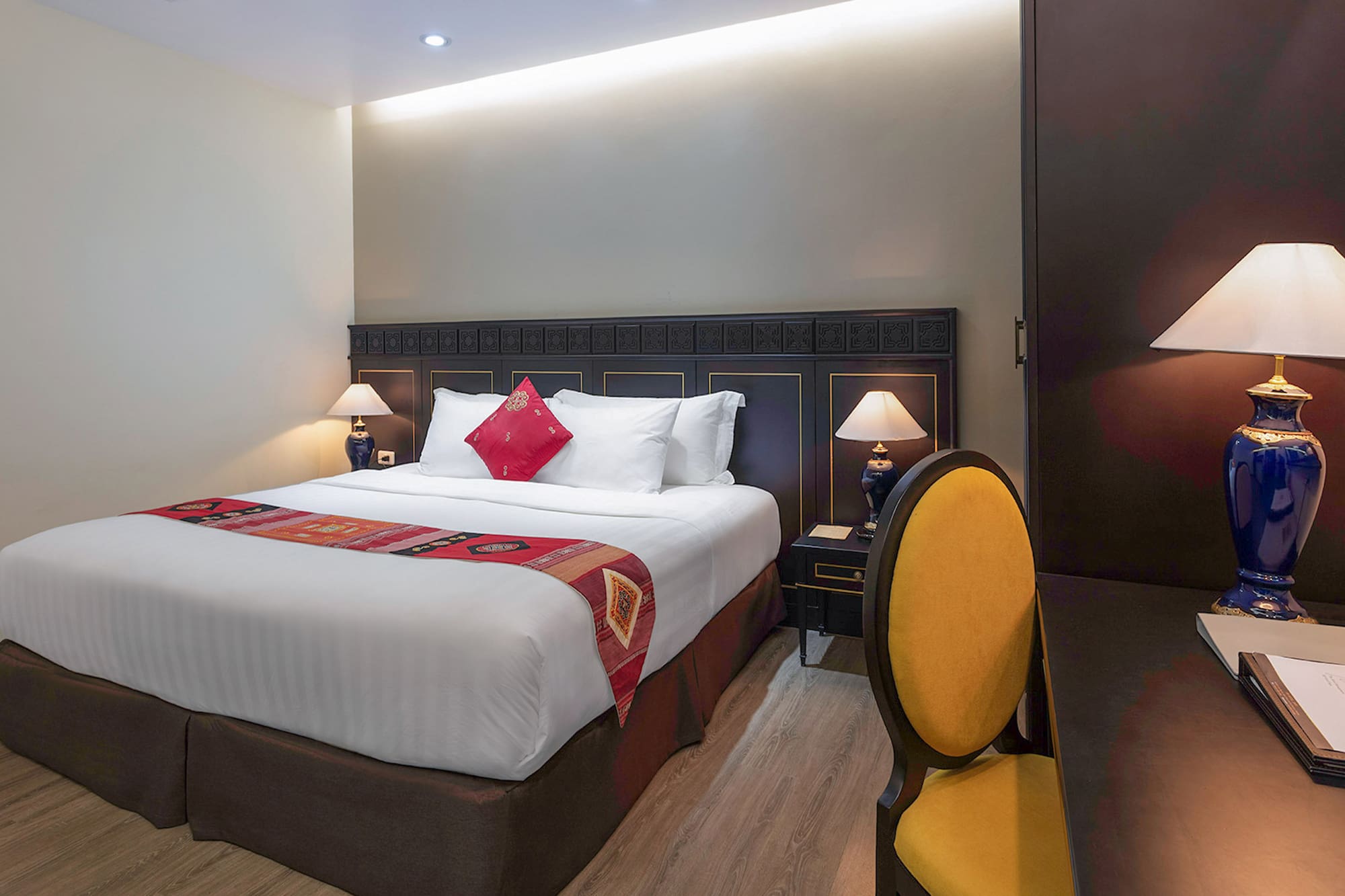 a bed with a red pillow and a yellow chair