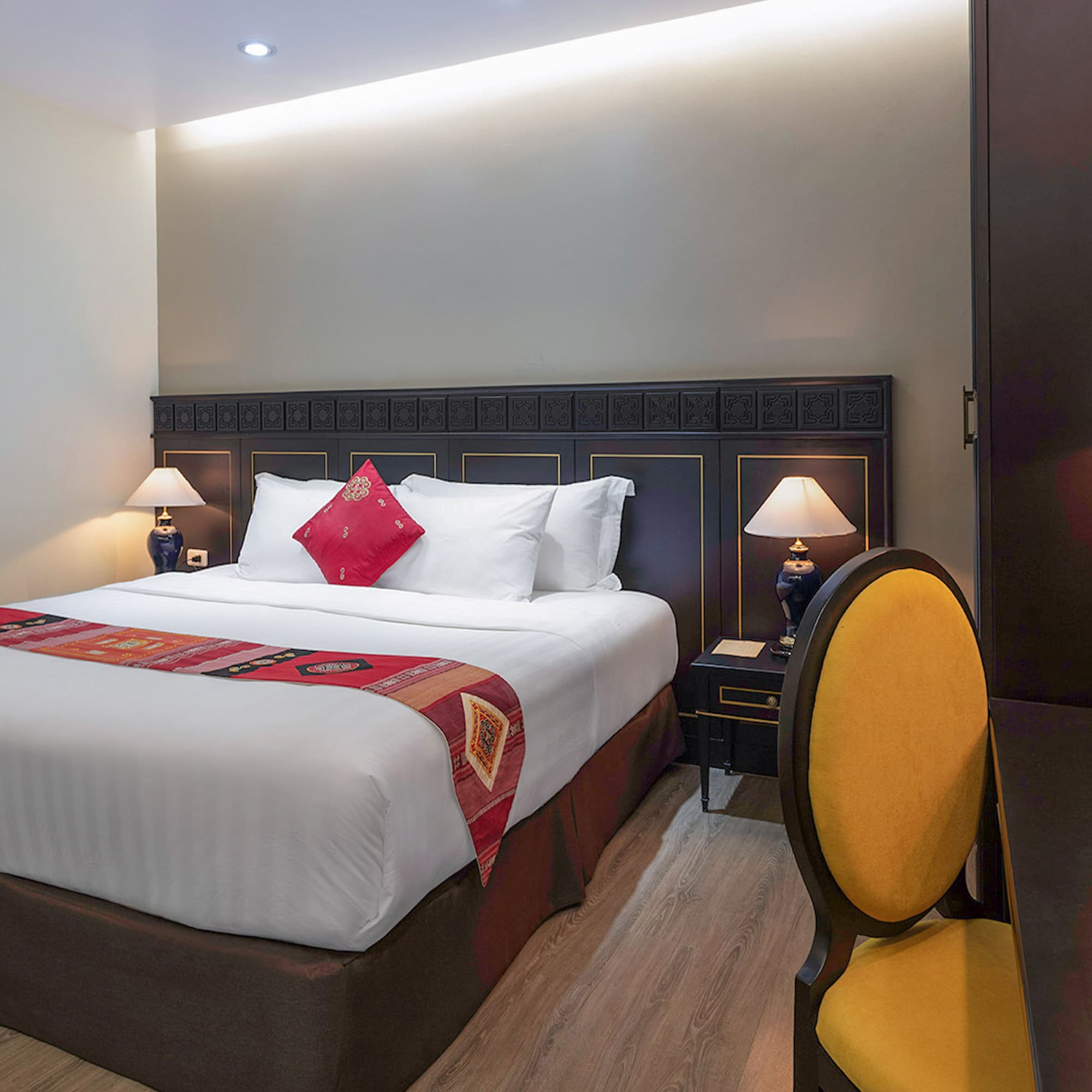 a bed with a red pillow and a yellow chair