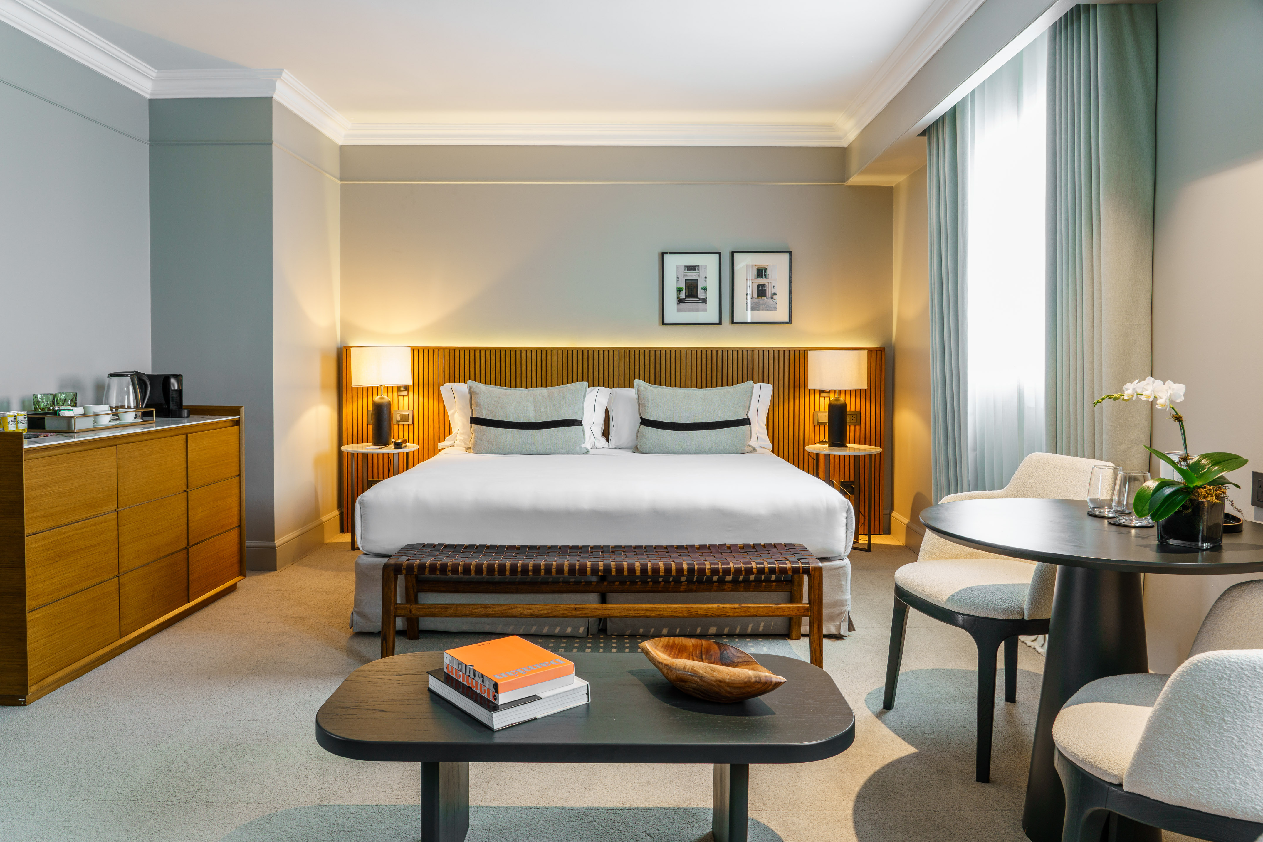 Stylish hotel bedroom with king bed, wood accents, and cozy seating.