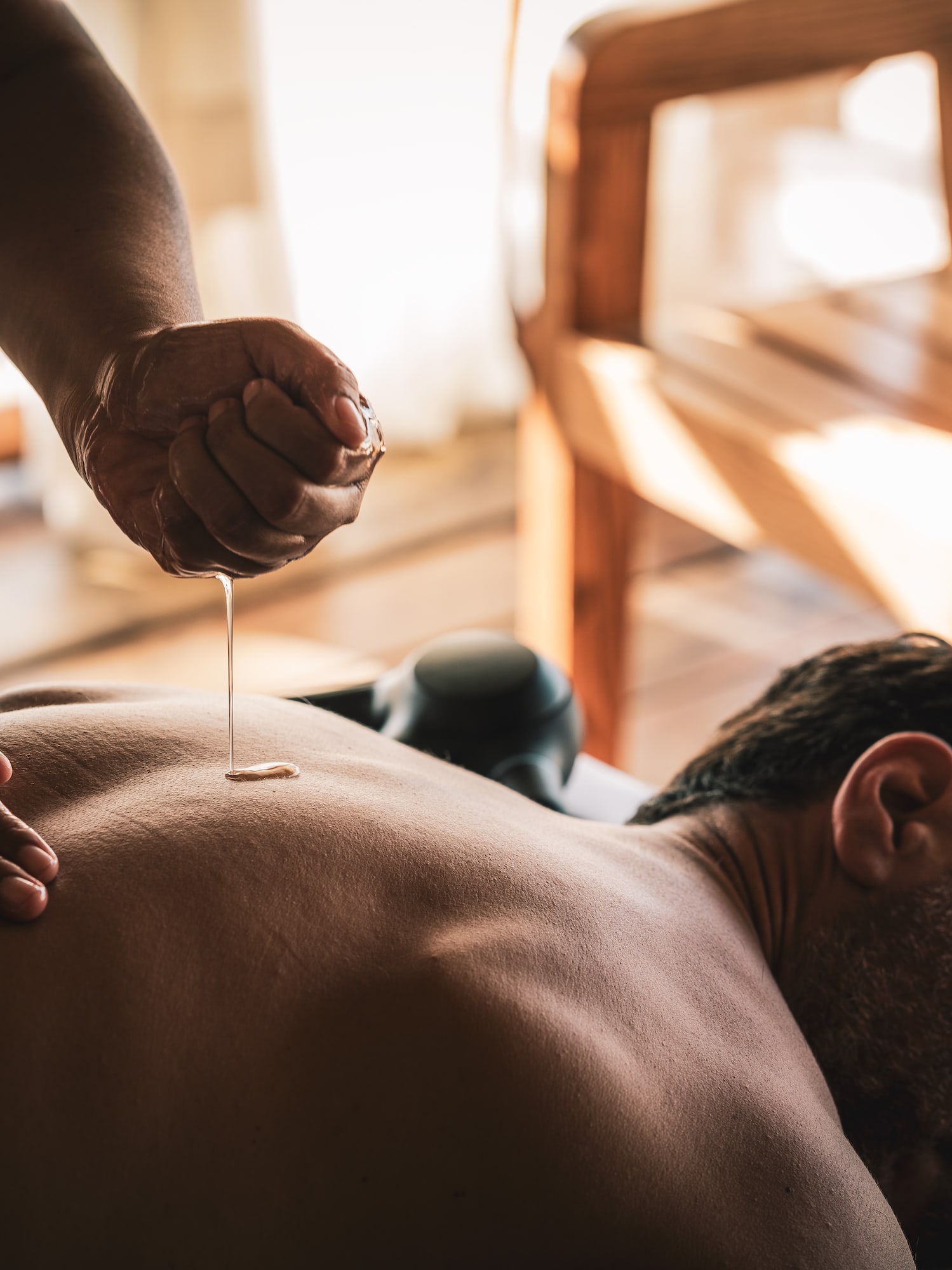 Masaje con aceite en la espalda de un hombre en un spa.