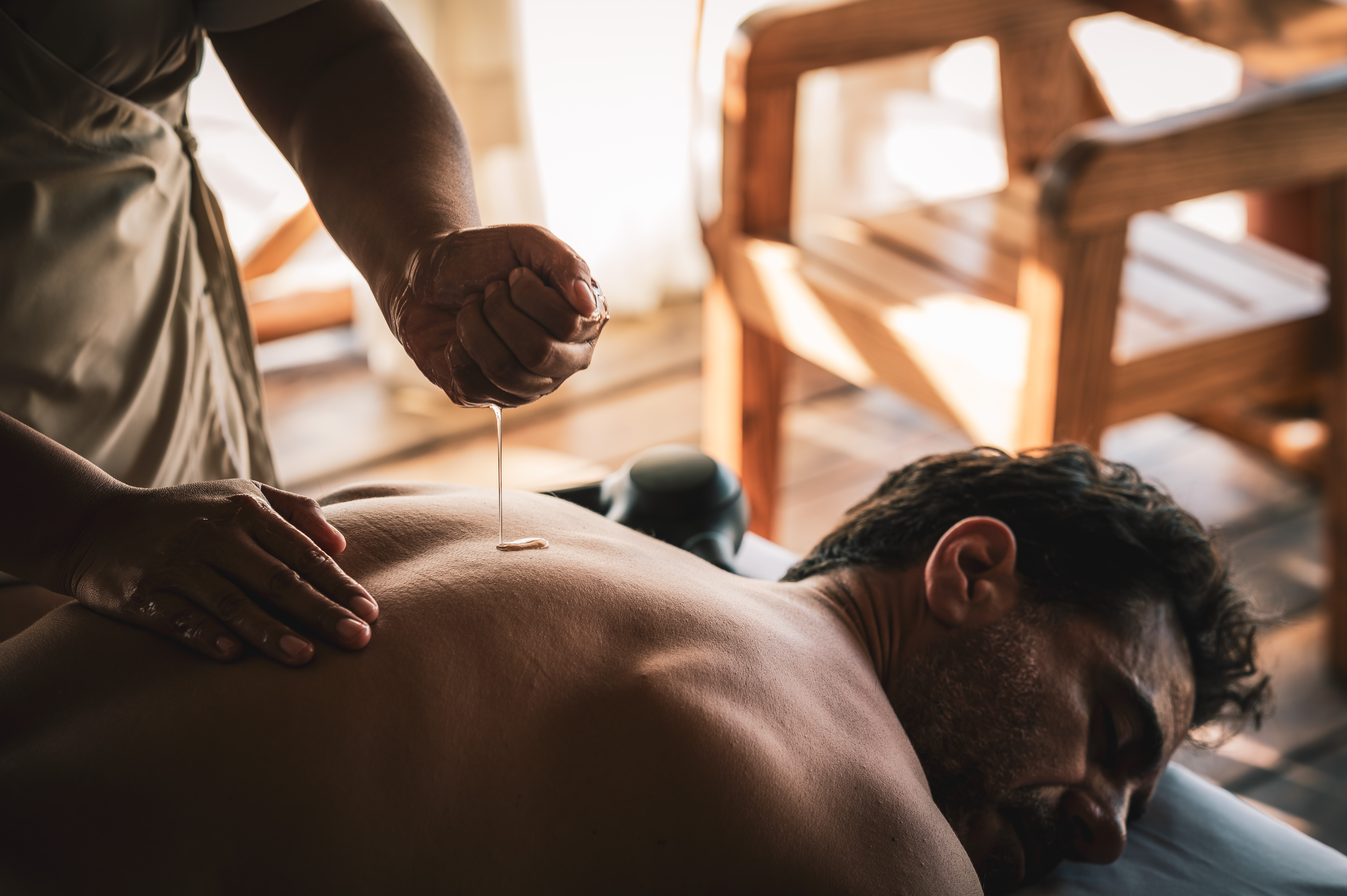 Masaje con aceite en la espalda de un hombre en un spa.