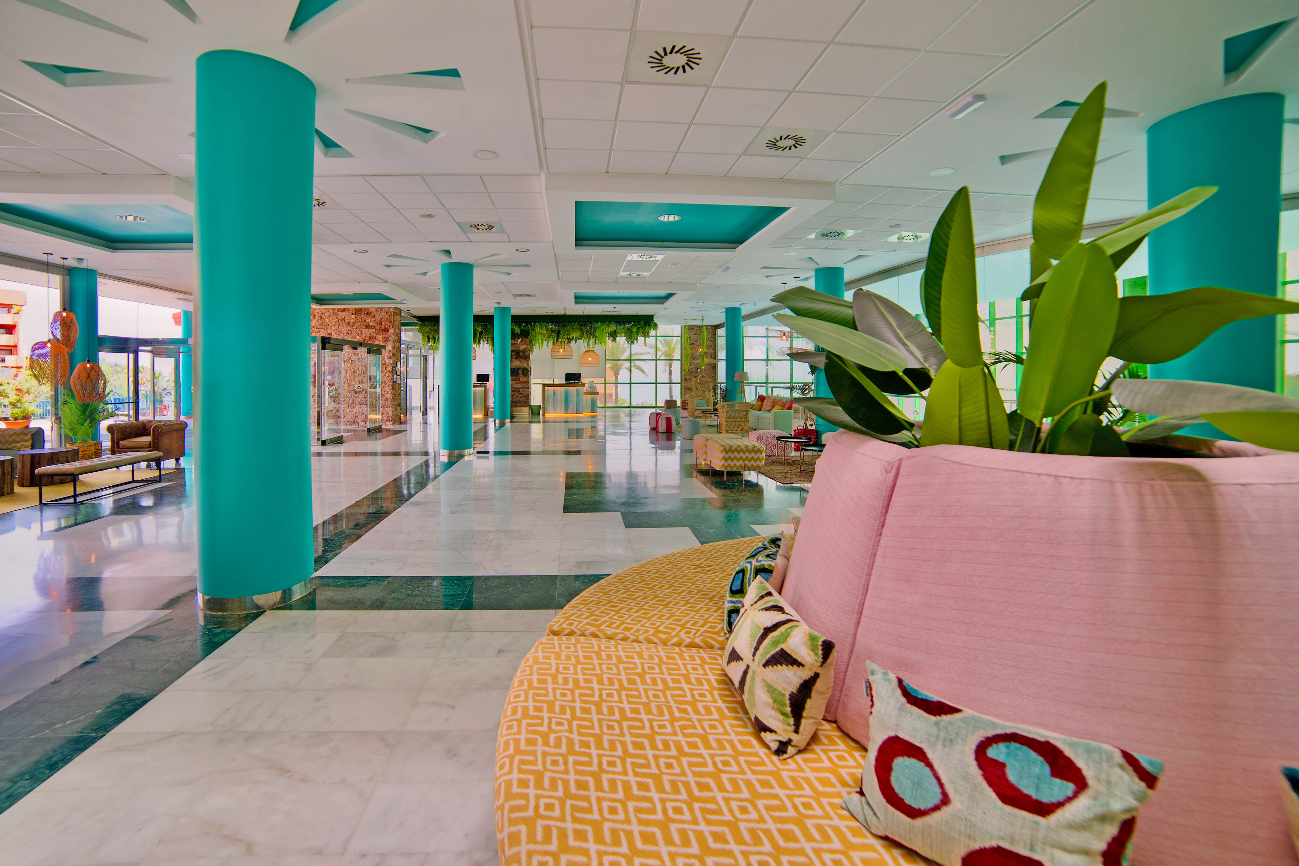 Vibrant hotel lobby with teal columns, marble floors, and colorful modern seating.
