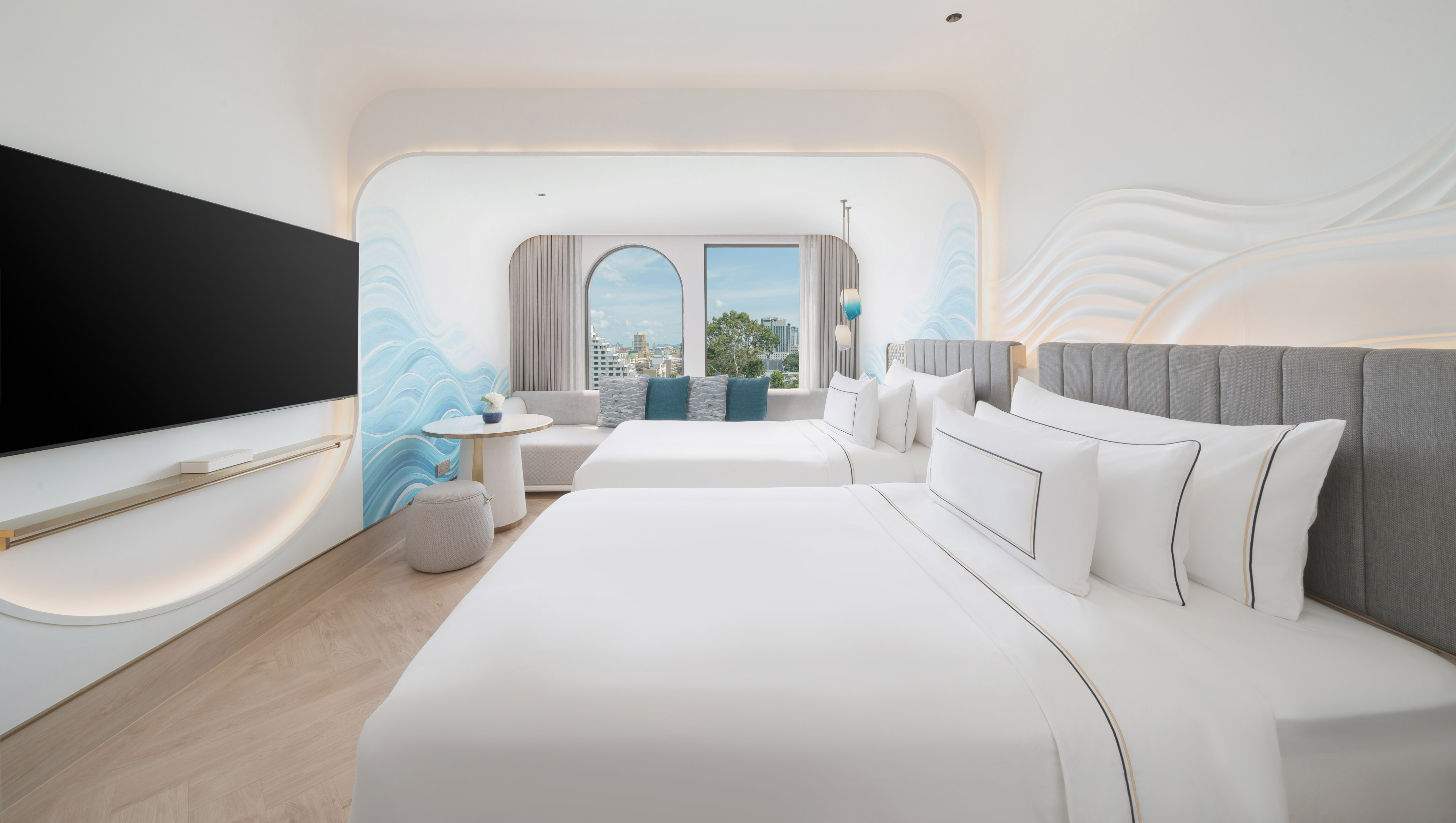Bright modern hotel room with two beds, city view, and elegant wave wall design.