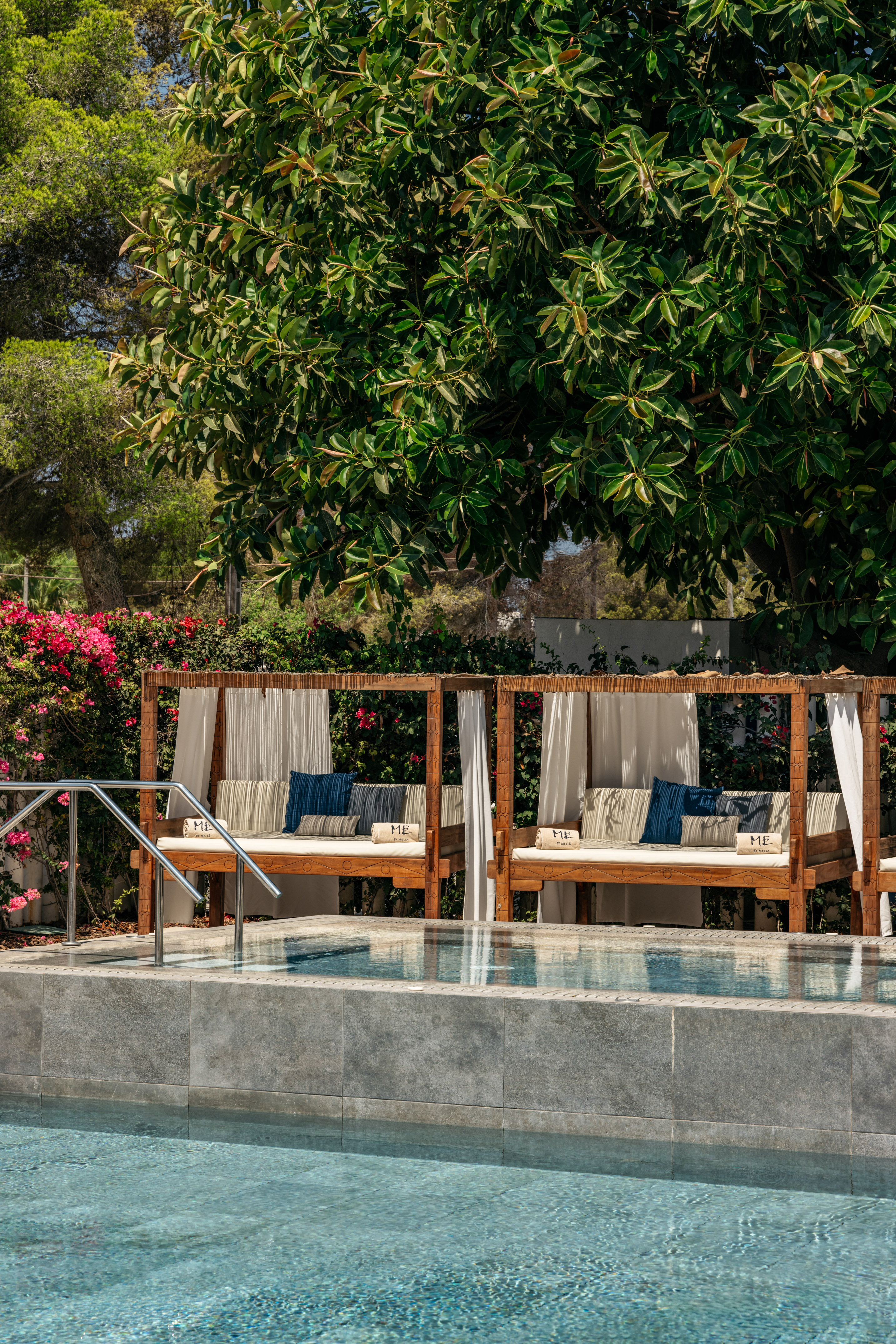 Luxury poolside daybeds with pillows by a blue pool, ME by Melia resort.