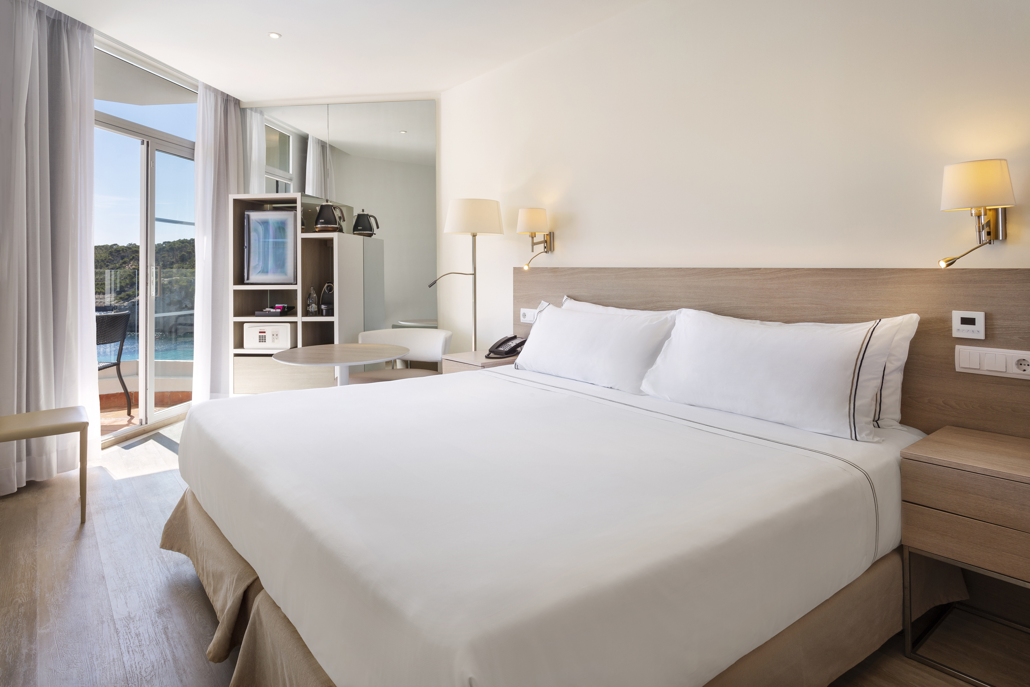 Contemporary hotel room with balcony, ocean views, and plush king bed.