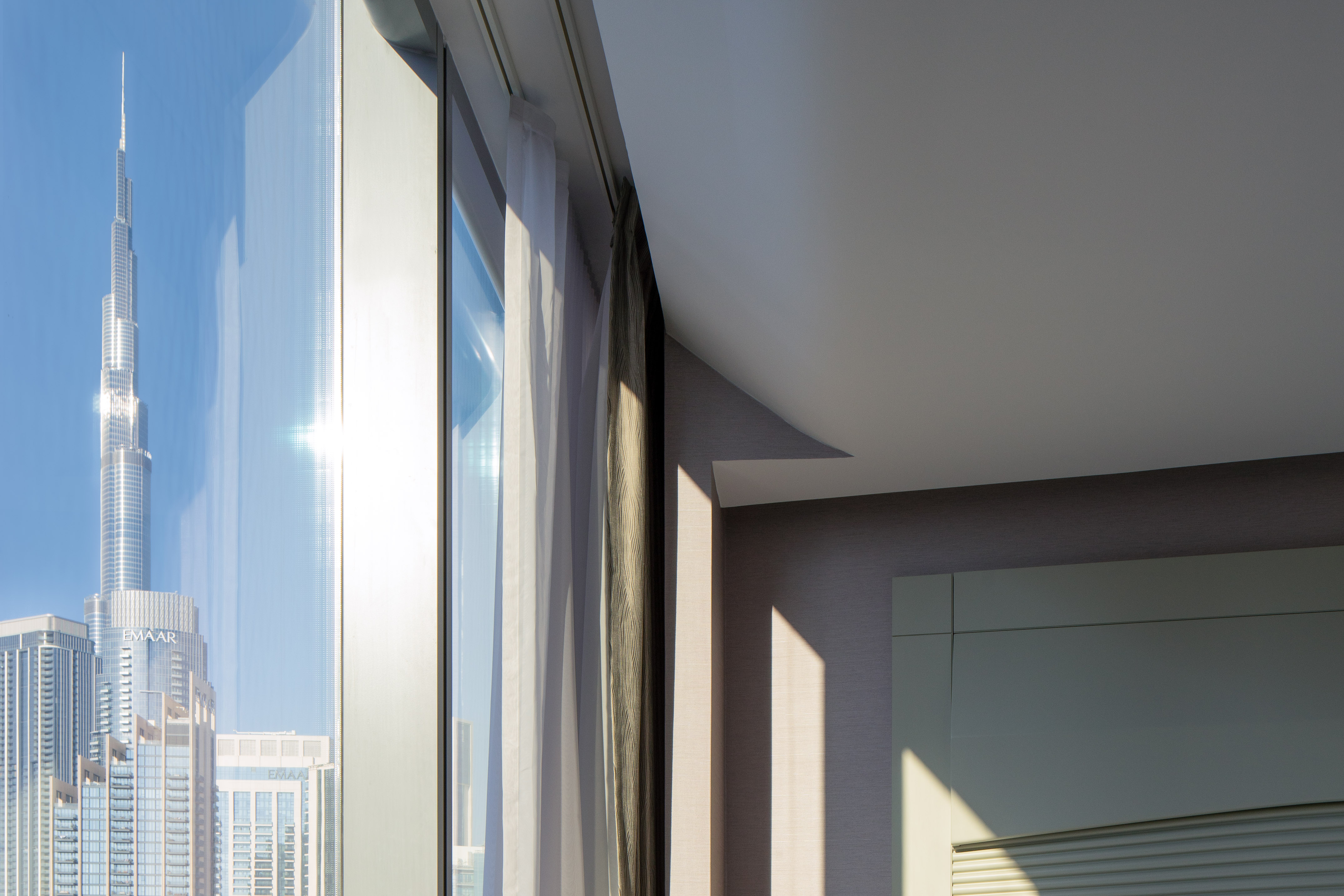Modern room window view of Dubai's Burj Khalifa with bright sunlight.