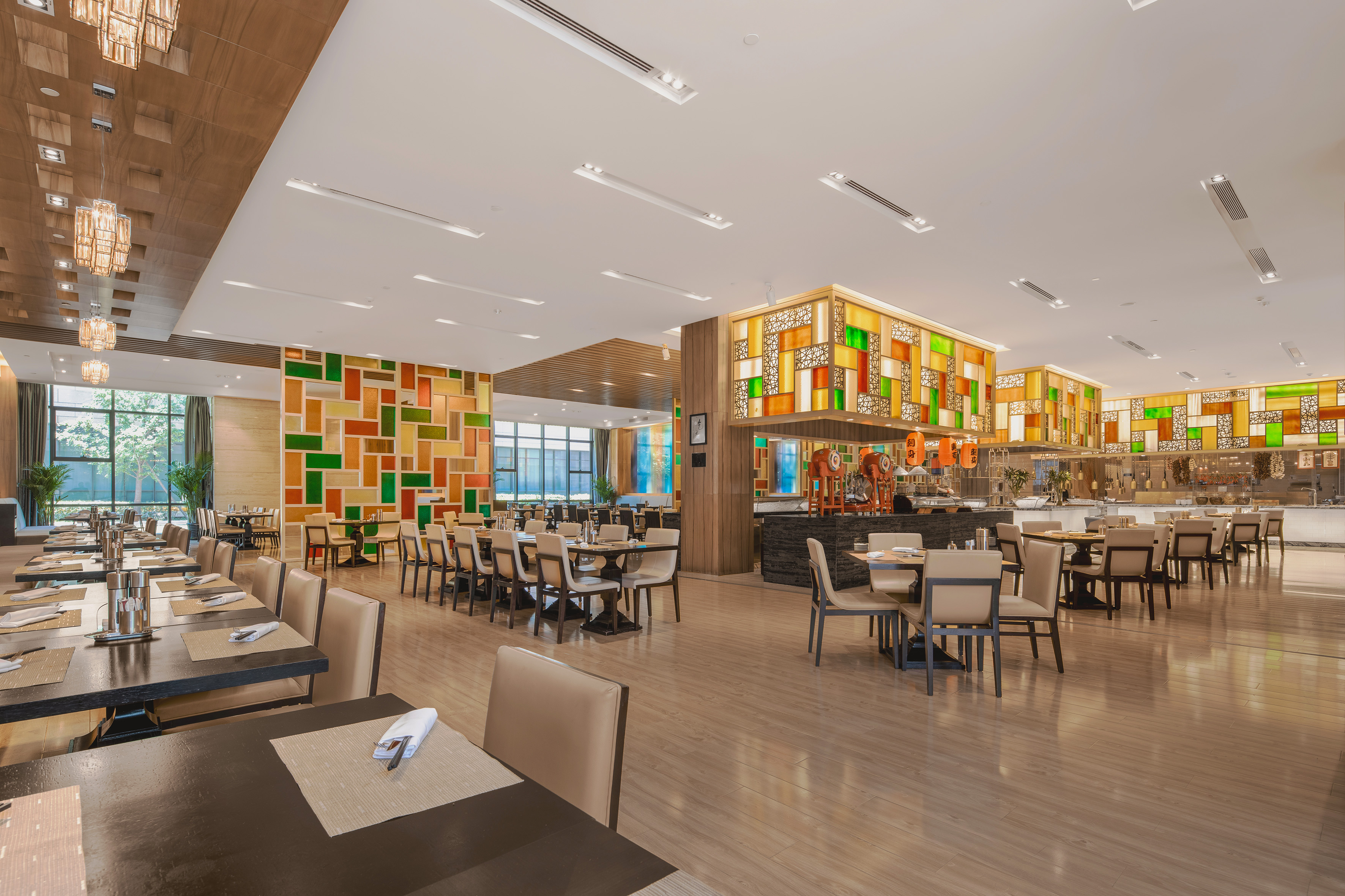 Modern hotel restaurant buffet with dining tables and colorful geometric decor.