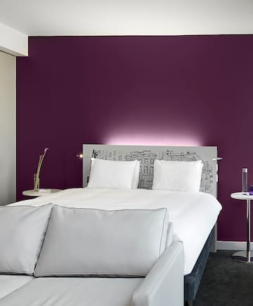 a bed with white pillows and a purple wall