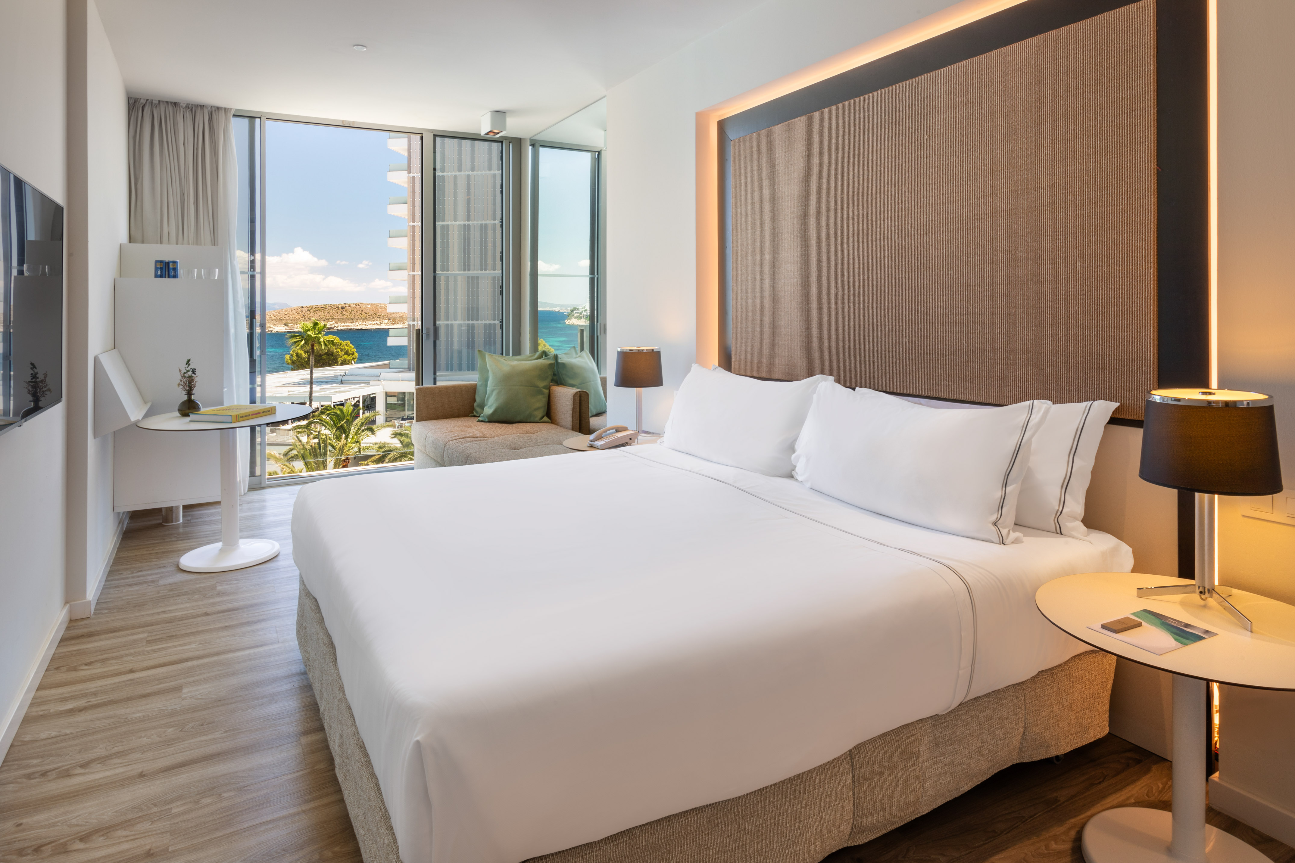 Luxury hotel bedroom with sea view balcony, white bed, and modern decor.