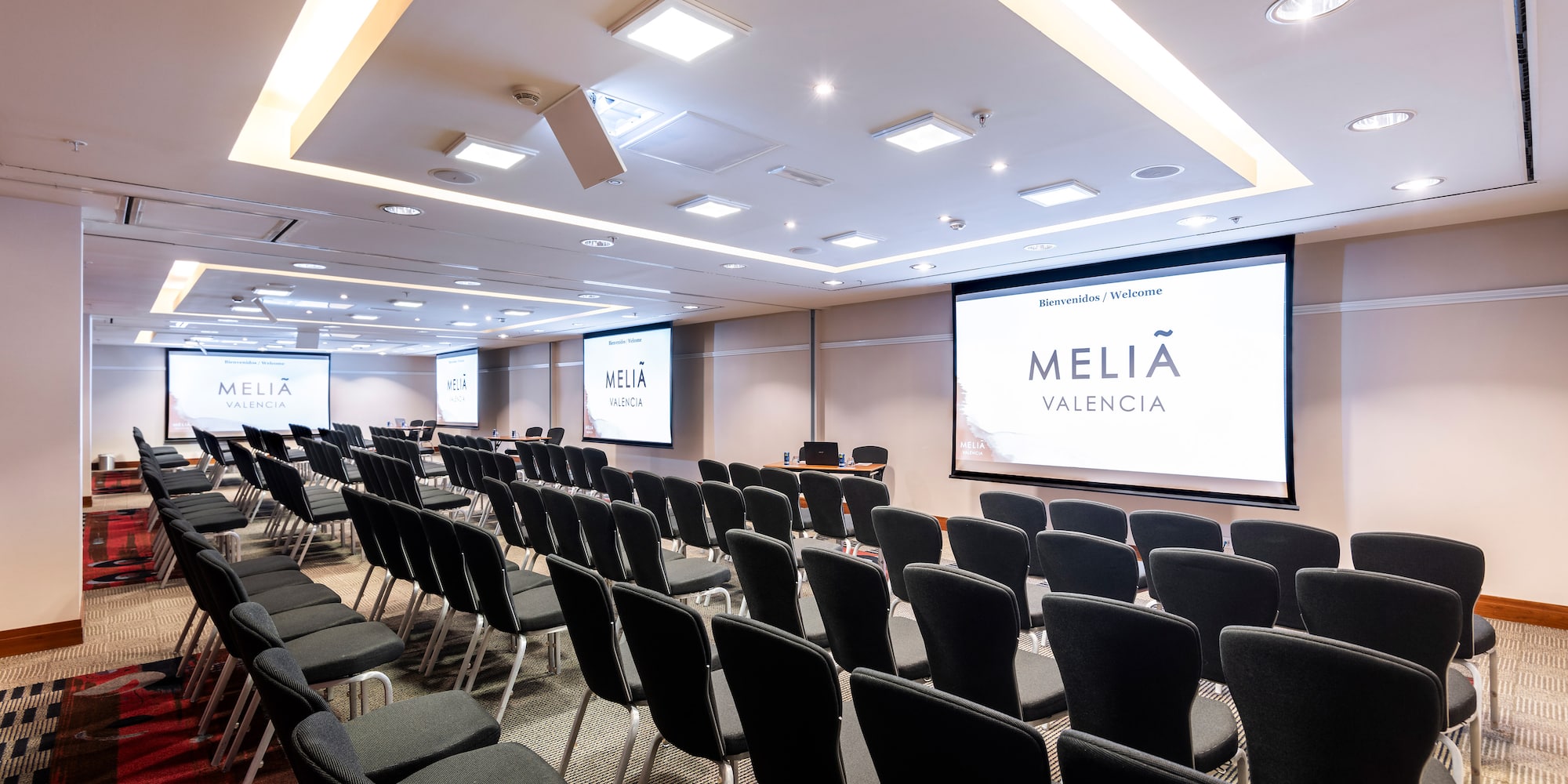 a room with rows of chairs and projector screens