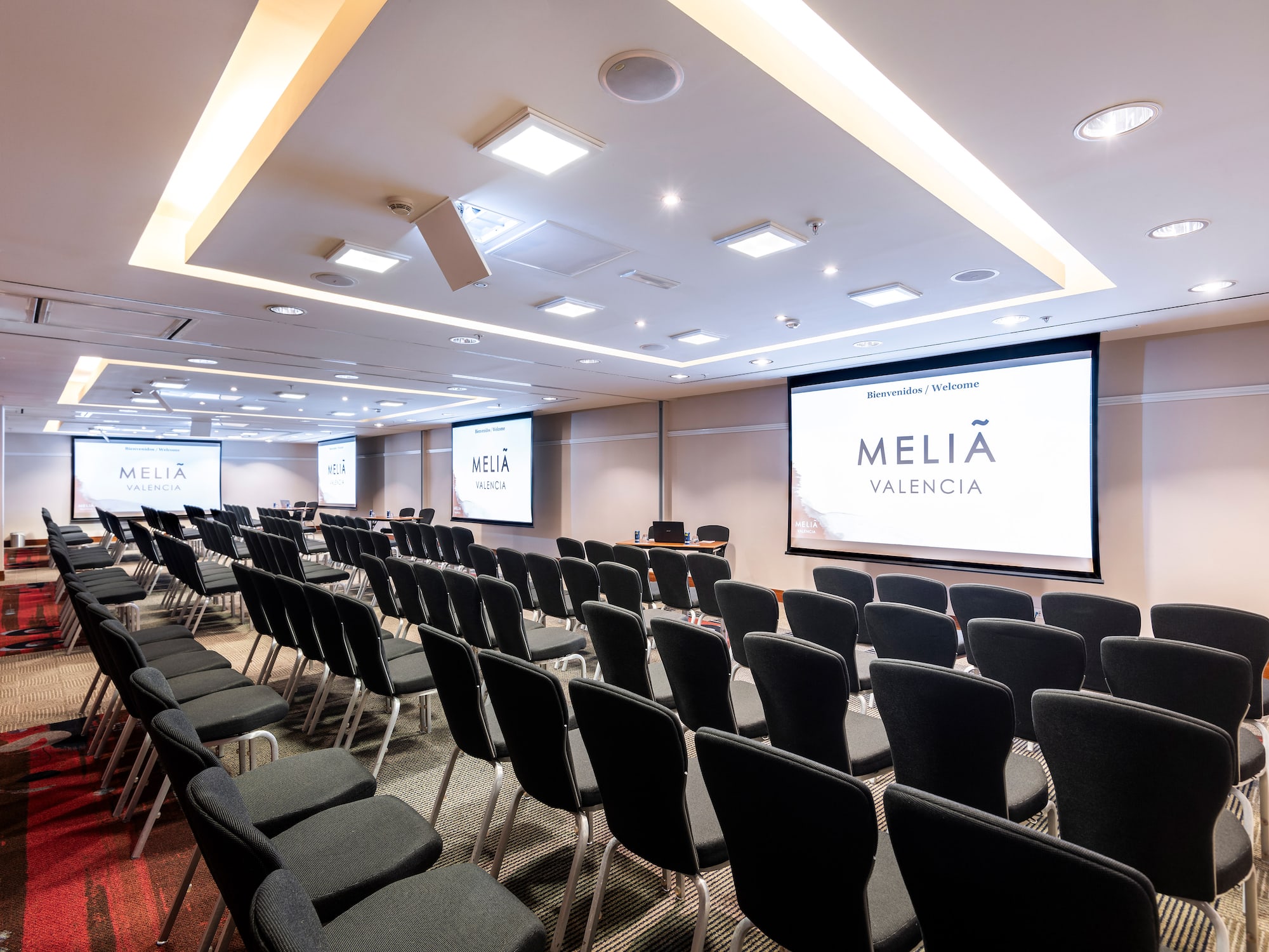 a room with rows of chairs and projector screens