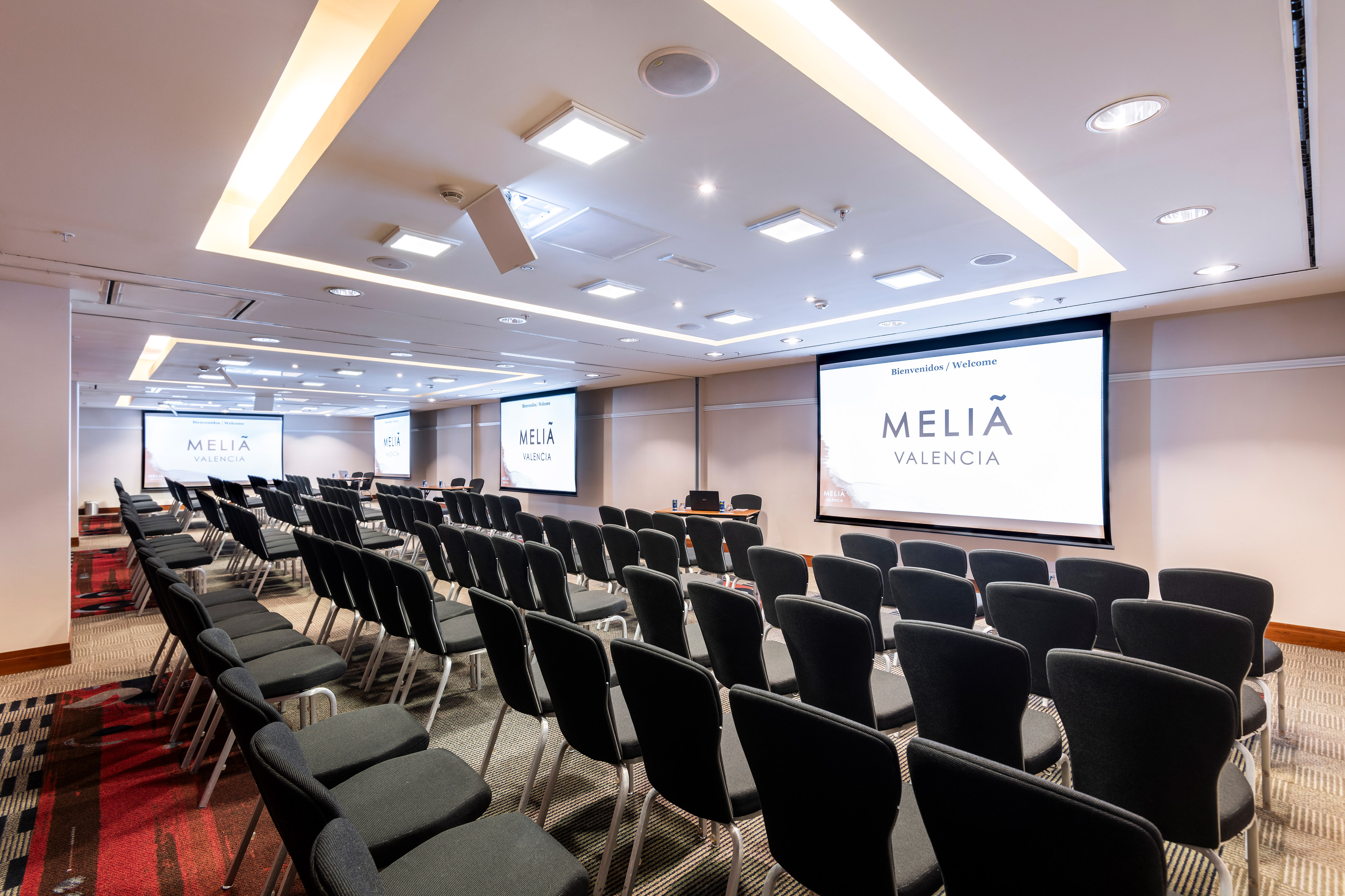 a room with rows of chairs and projector screens