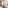 Modern hotel room: open wardrobe, desk area, wall TV, and plant.