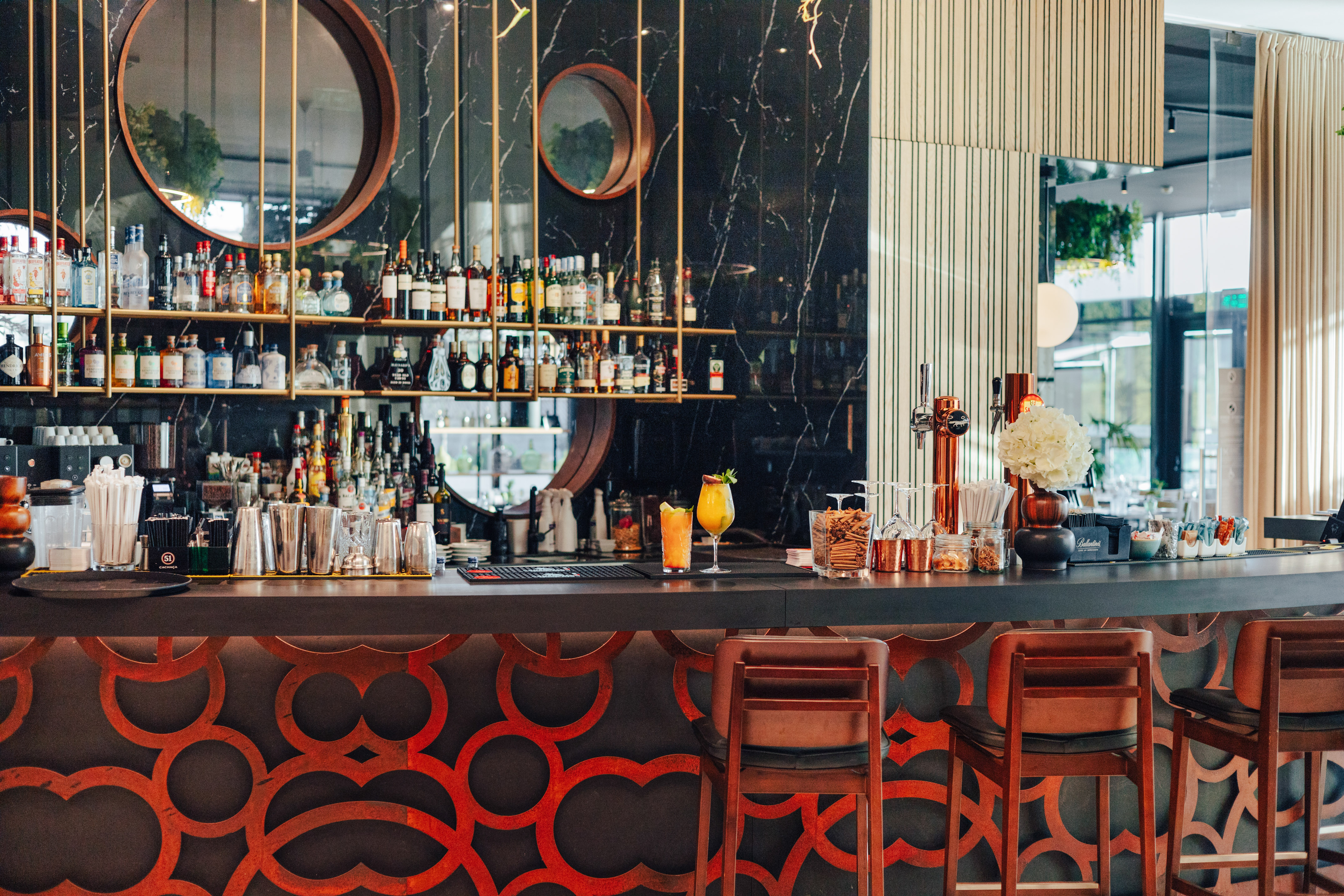 Modern bar with cocktails, liquor, black marble, and geometric pattern.
